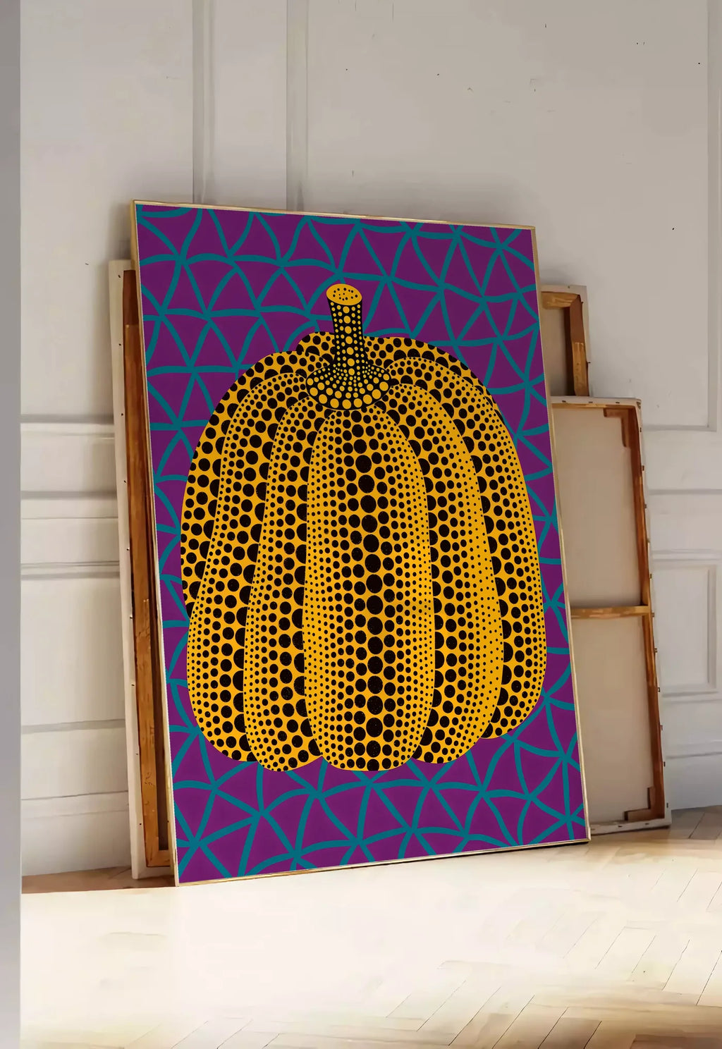 Tirage encadrable affiche Kusama citrouille jaune a pois sur fond violet a filet bleu, posee au sol dans une entree lumineuse, contre un mur a panneaux blancs, a cote de chassis en bois empiles