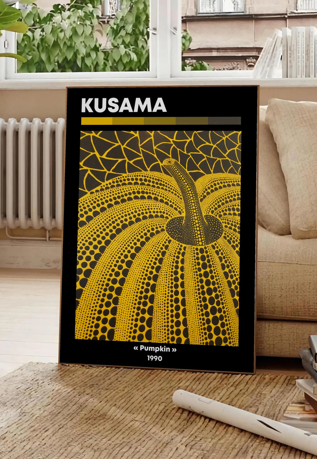 Poster affiche Kusama citrouille jaune a pois vue en contre-plongee sur fond noir, posee au sol dans un salon parisien, devant une grande fenetre donnant sur un immeuble haussmannien, entre un ficus et un canape creme