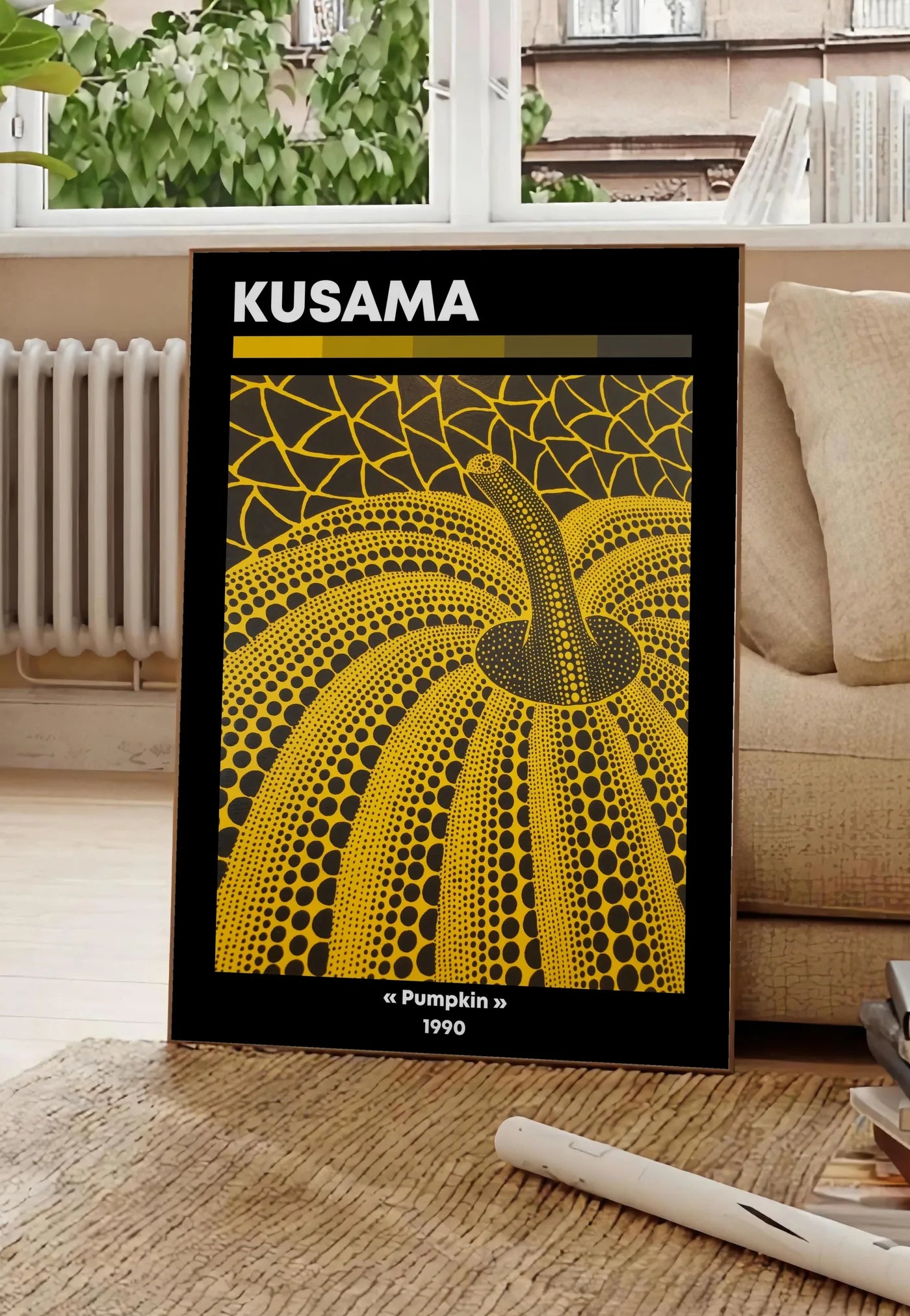 Poster affiche Kusama citrouille jaune a pois vue en contre-plongee sur fond noir, posee au sol dans un salon parisien, devant une grande fenetre donnant sur un immeuble haussmannien, entre un ficus et un canape creme