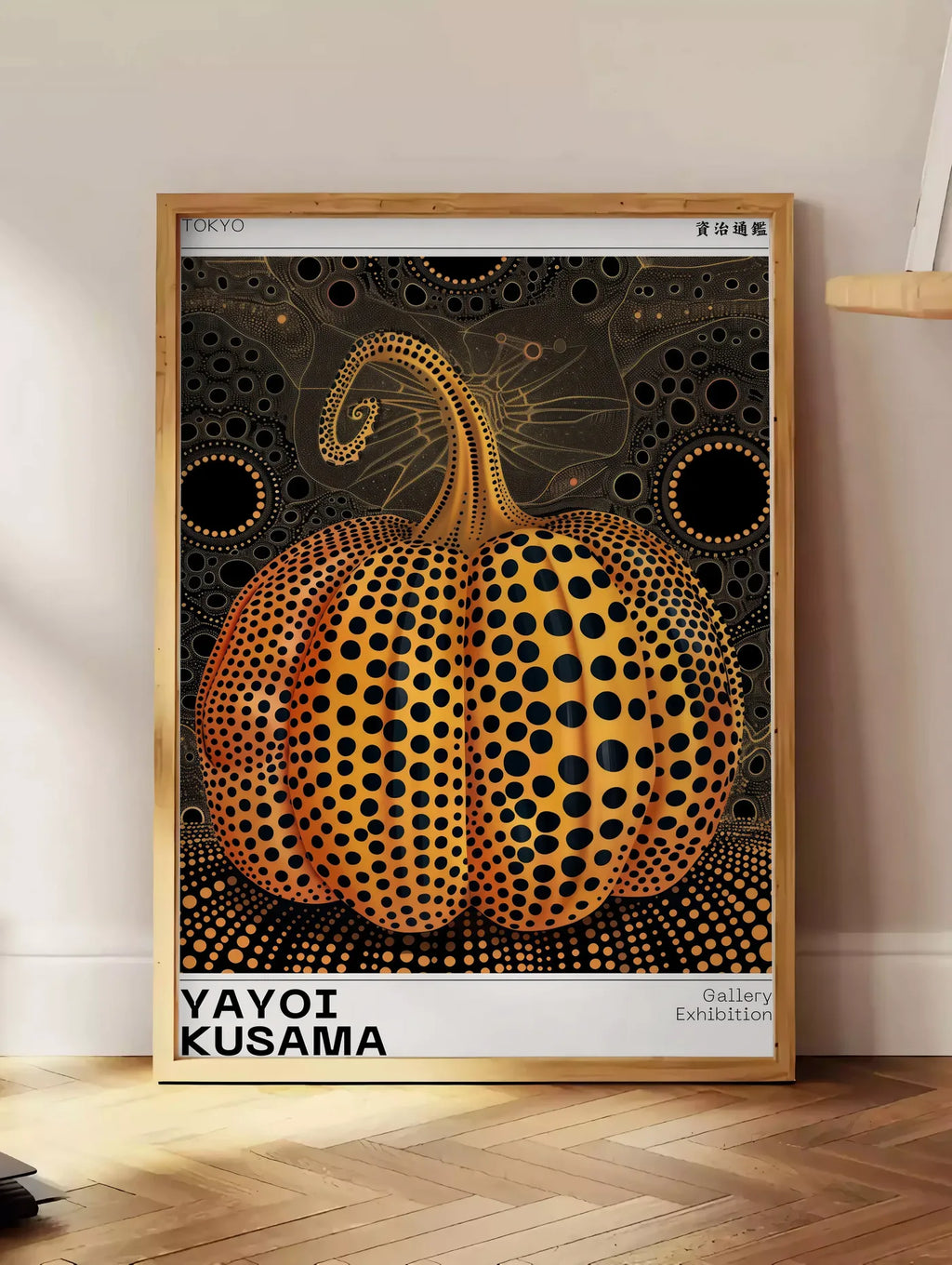 Estampe affiche Kusama citrouille orange a pois sur fond noir, posee au sol dans un coin salon, sur un parquet a chevrons, pres d'une table d'appoint en chene chargee de livres