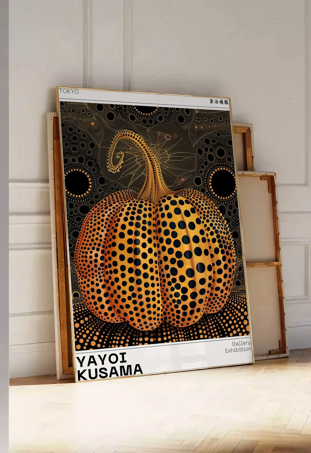 Tirage encadrable affiche Kusama citrouille orange a pois sur fond noir, posee au sol dans une entree lumineuse, contre un mur a panneaux blancs, a cote de chassis en bois empiles