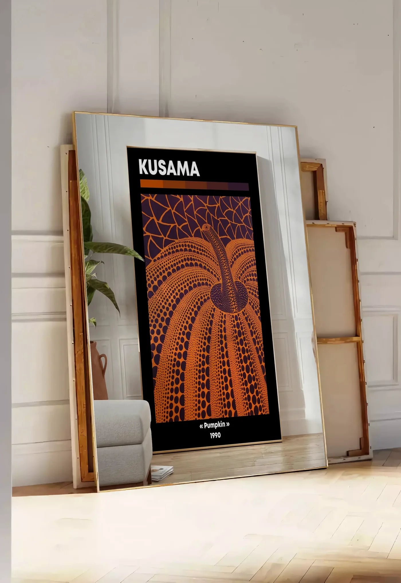 Tirage encadrable affiche Kusama citrouille orange a pois sur fond violet, posee au sol dans une entree lumineuse, contre un mur a panneaux blancs, a cote de chassis en bois empiles