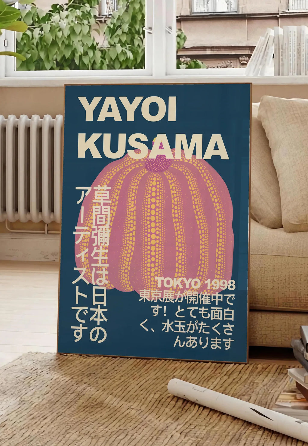 Poster affiche Kusama citrouille rose a pois sur fond bleu nuit, posee au sol dans un salon parisien, devant une grande fenetre donnant sur un immeuble haussmannien, entre un ficus et un canape creme