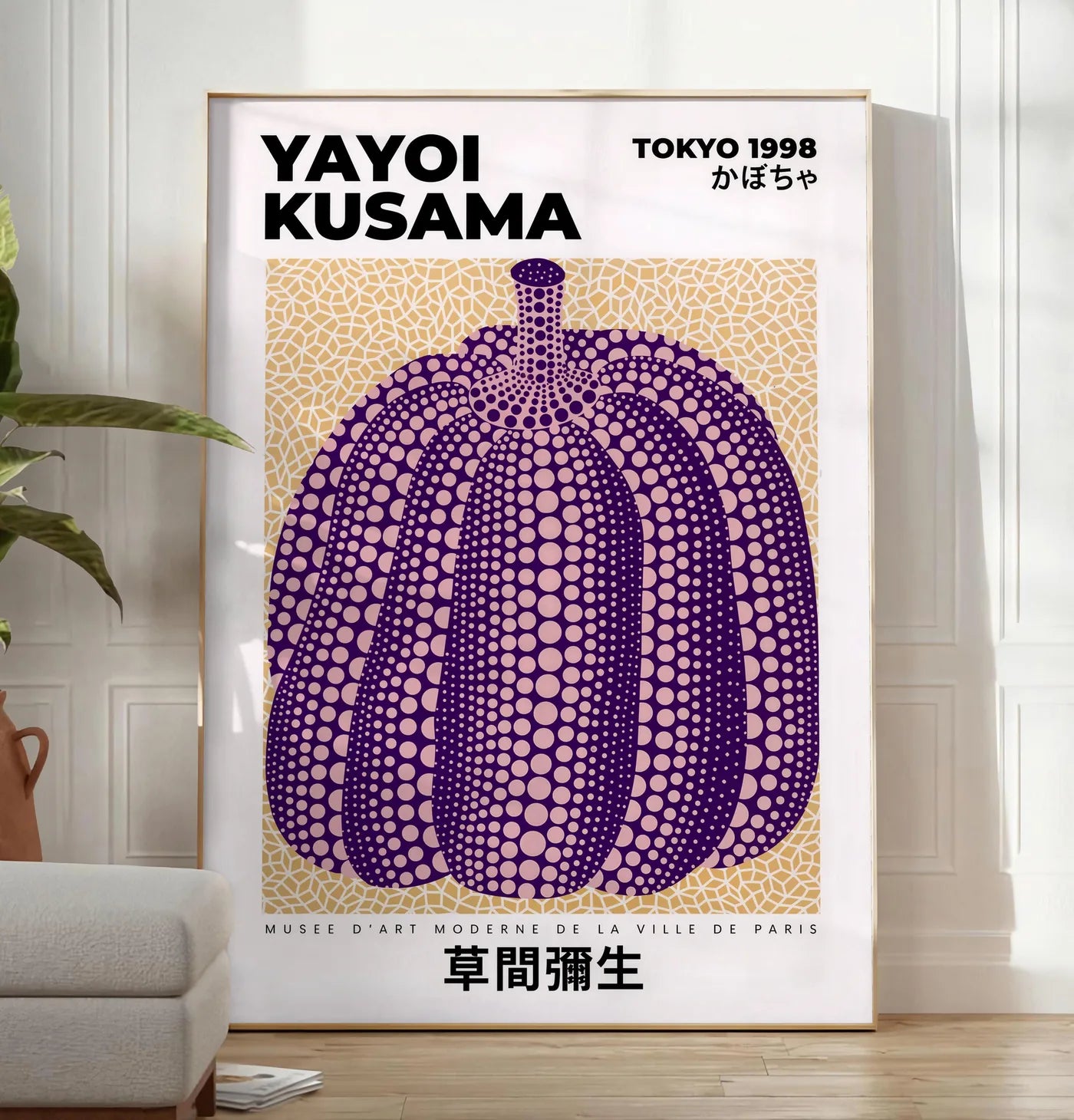 Reproduction affiche Kusama citrouille violette a pois sur fond beige, posee au sol dans un salon minimaliste clair, a cote d'un canape beige et d'une plante verte, sur un parquet clair