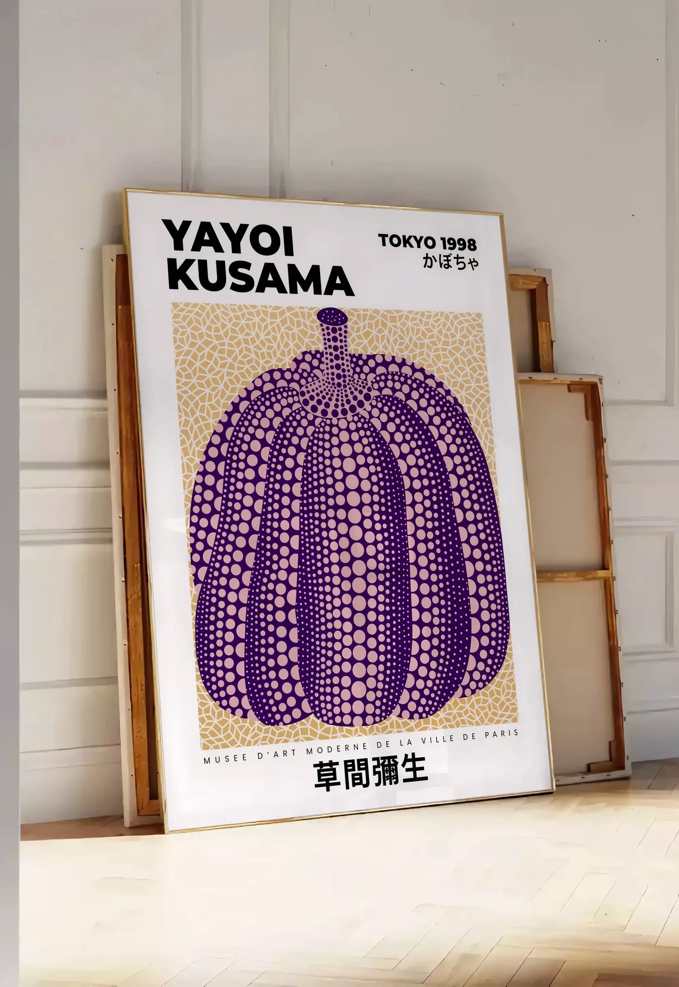 Tirage encadrable affiche Kusama citrouille violette a pois sur fond beige, posee au sol dans une entree lumineuse, contre un mur a panneaux blancs, a cote de chassis en bois empiles
