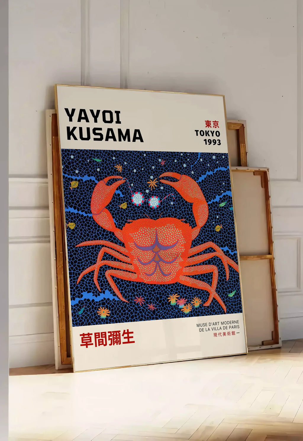 Tirage encadrable affiche crabe rouge a pois de Kusama art japonais, posee au sol dans une entree lumineuse, contre un mur a panneaux blancs, a cote de chassis en bois empiles