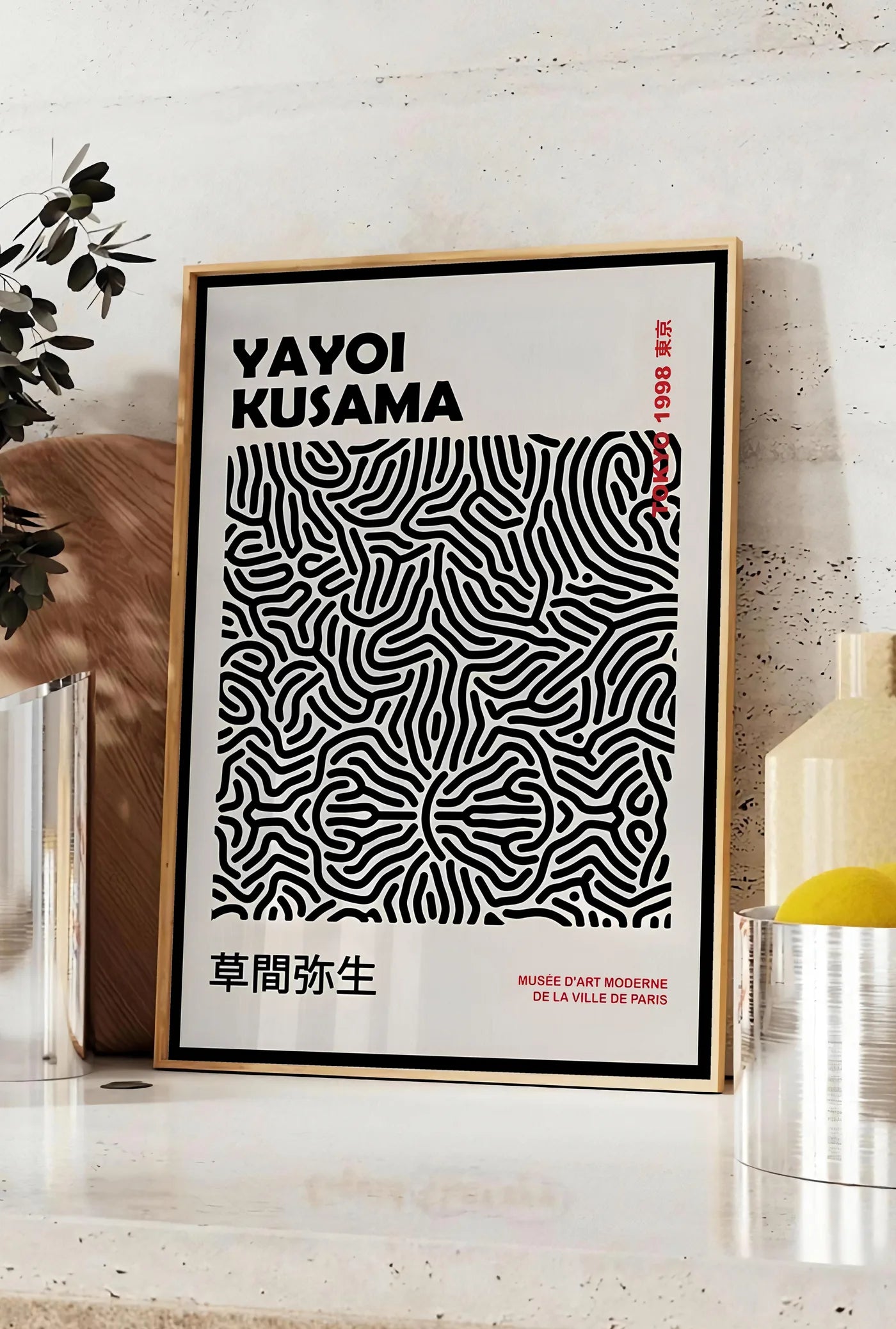 Affiche affiche filet infini de Kusama art japonais, posee sur un plan de travail de cuisine en pierre claire, entre une branche d'eucalyptus en vase et un bocal de citrons