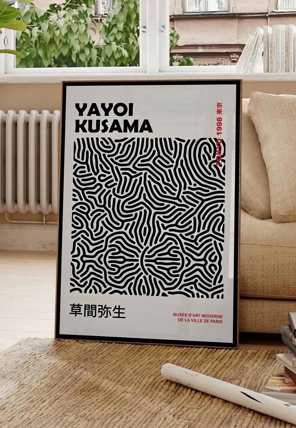 Poster affiche filet infini de Kusama art japonais, posee au sol dans un salon parisien, devant une grande fenetre donnant sur un immeuble haussmannien, entre un ficus et un canape creme