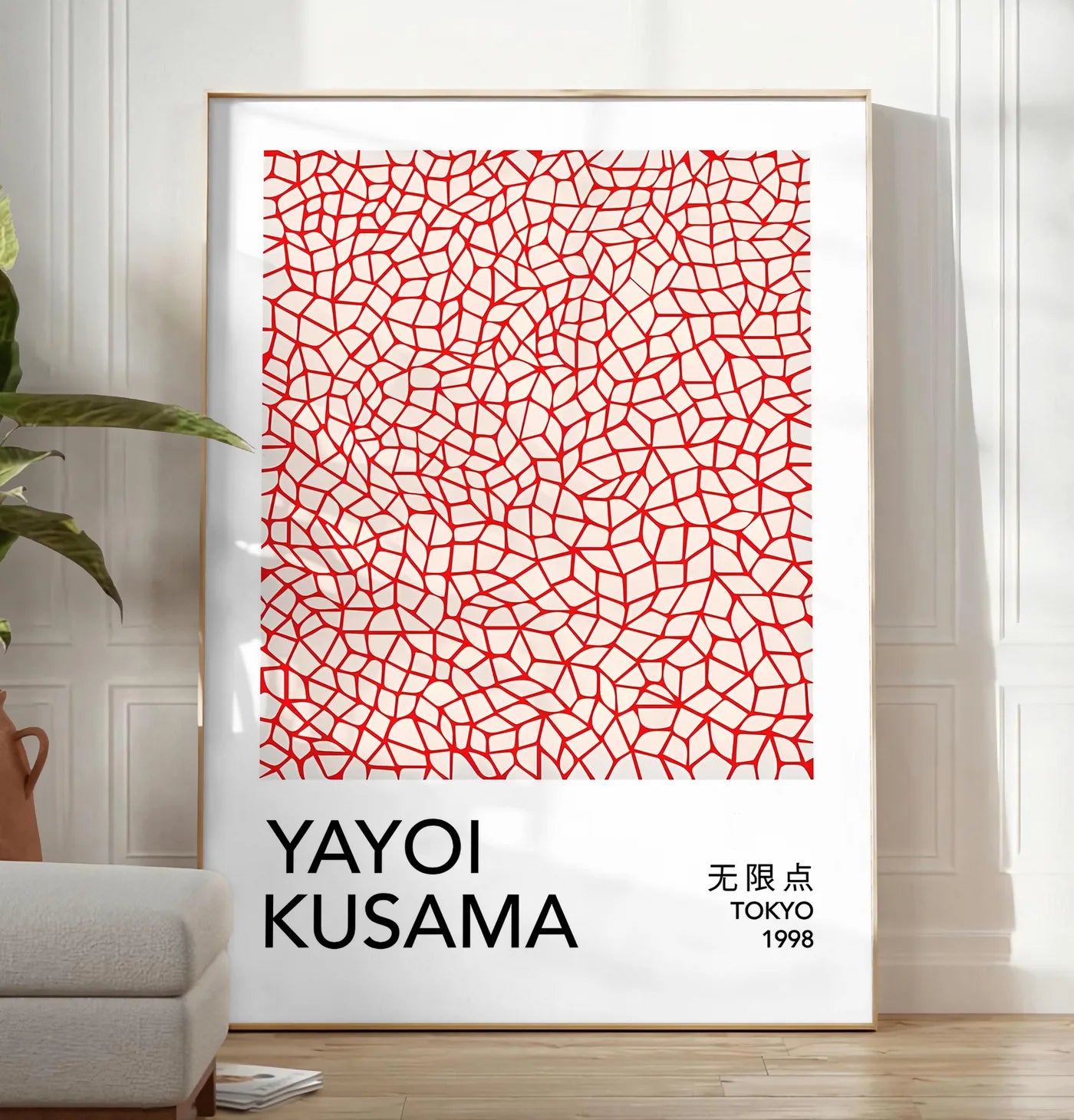 Reproduction affiche filet infini rouge de Kusama art japonais, posee au sol dans un salon minimaliste clair, a cote d'un canape beige et d'une plante verte, sur un parquet clair