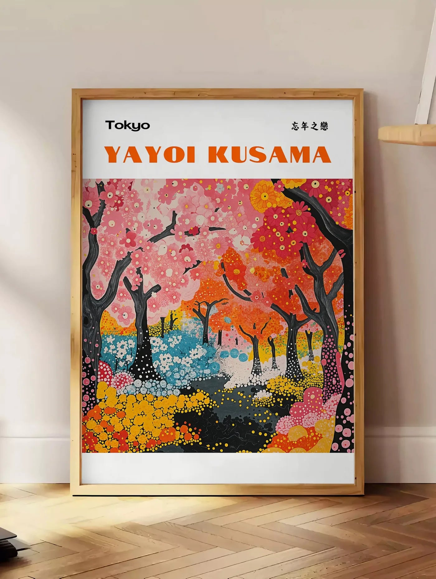 Estampe affiche foret printaniere de Kusama art japonais, posee au sol dans un coin salon, sur un parquet a chevrons, pres d'une table d'appoint en chene chargee de livres