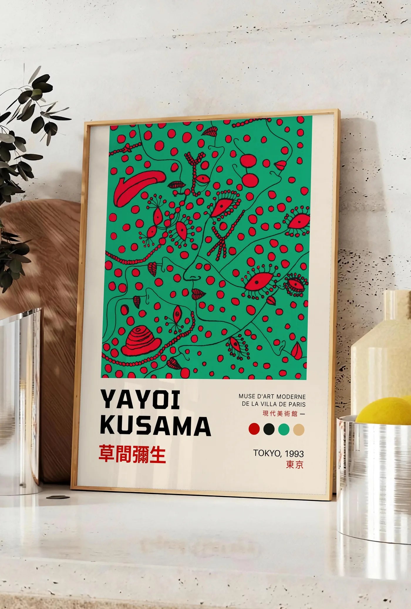 Affiche affiche formes rouges de Kusama art japonais, posee sur un plan de travail de cuisine en pierre claire, entre une branche d'eucalyptus en vase et un bocal de citrons