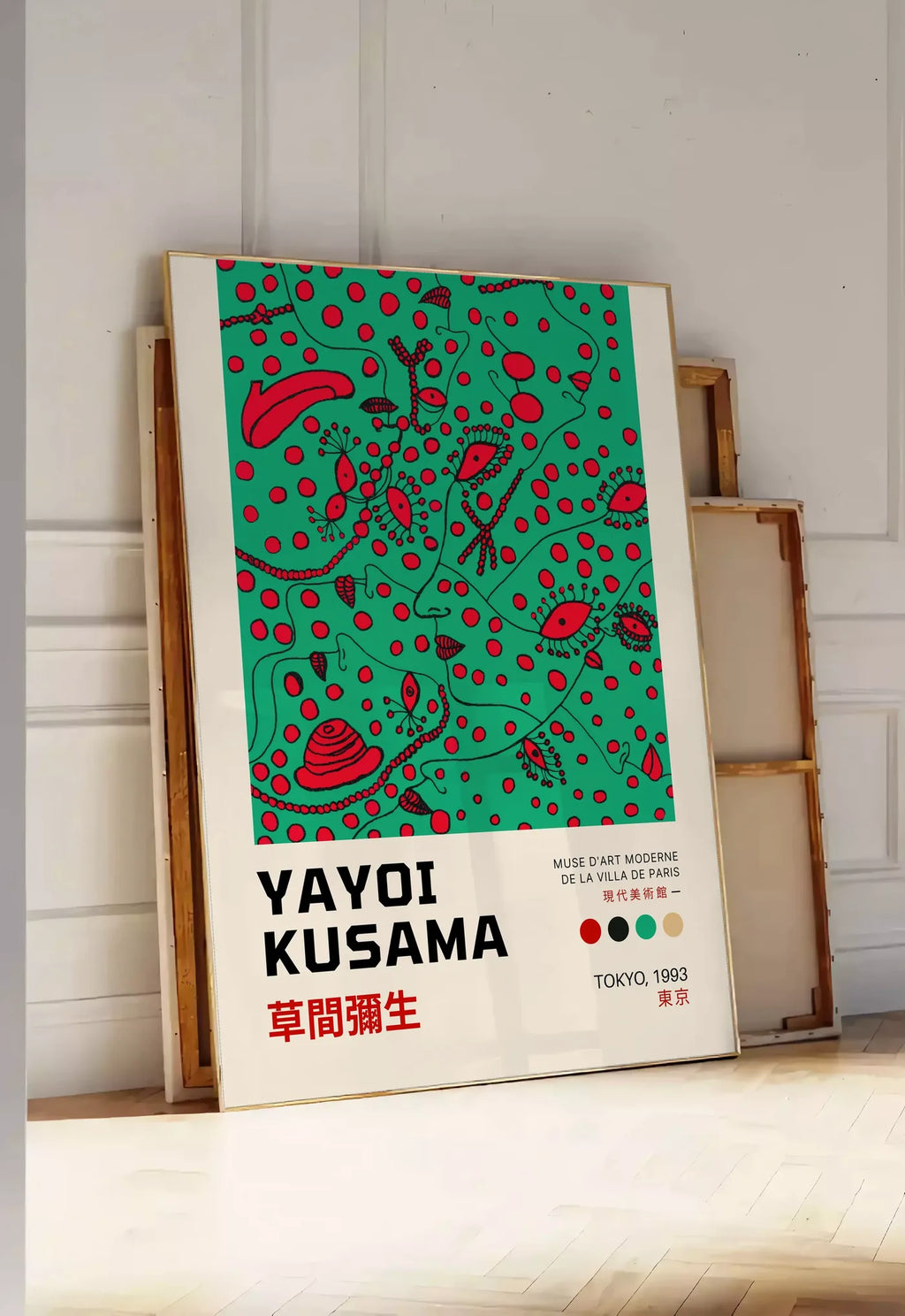 Tirage encadrable affiche formes rouges de Kusama art japonais, posee au sol dans une entree lumineuse, contre un mur a panneaux blancs, a cote de chassis en bois empiles