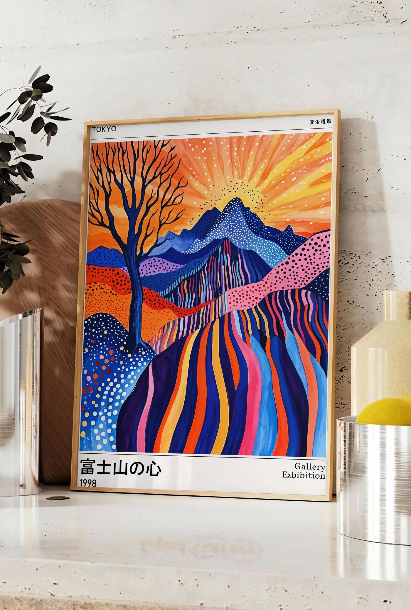 Affiche affiche arbre et soleil de Kusama art japonais, posee sur un plan de travail de cuisine en pierre claire, entre une branche d'eucalyptus en vase et un bocal de citrons