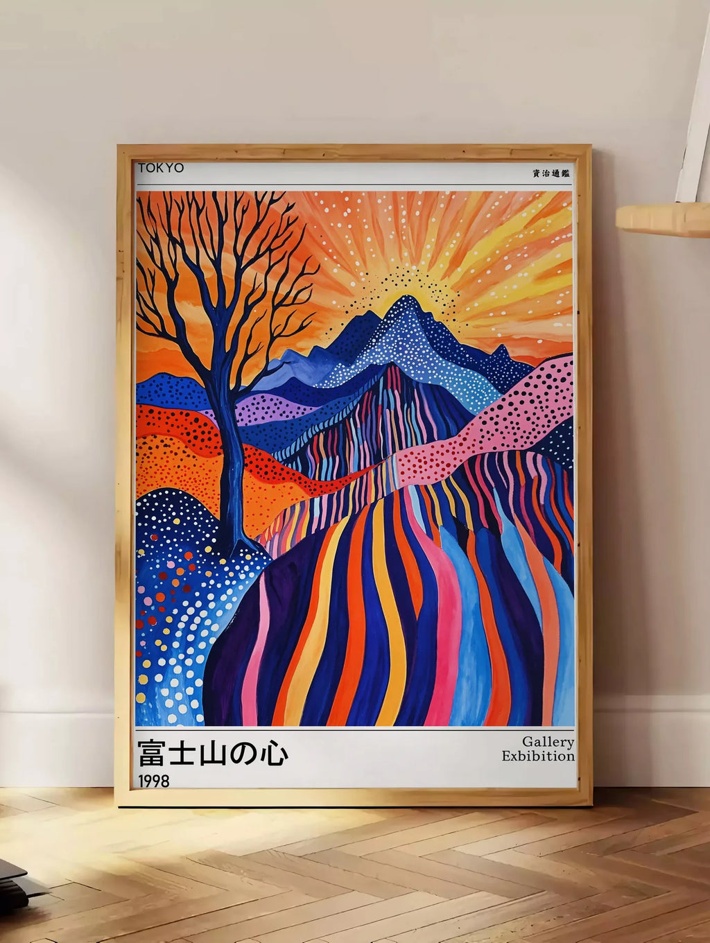 Estampe affiche arbre et soleil de Kusama art japonais, posee au sol dans un coin salon, sur un parquet a chevrons, pres d'une table d'appoint en chene chargee de livres