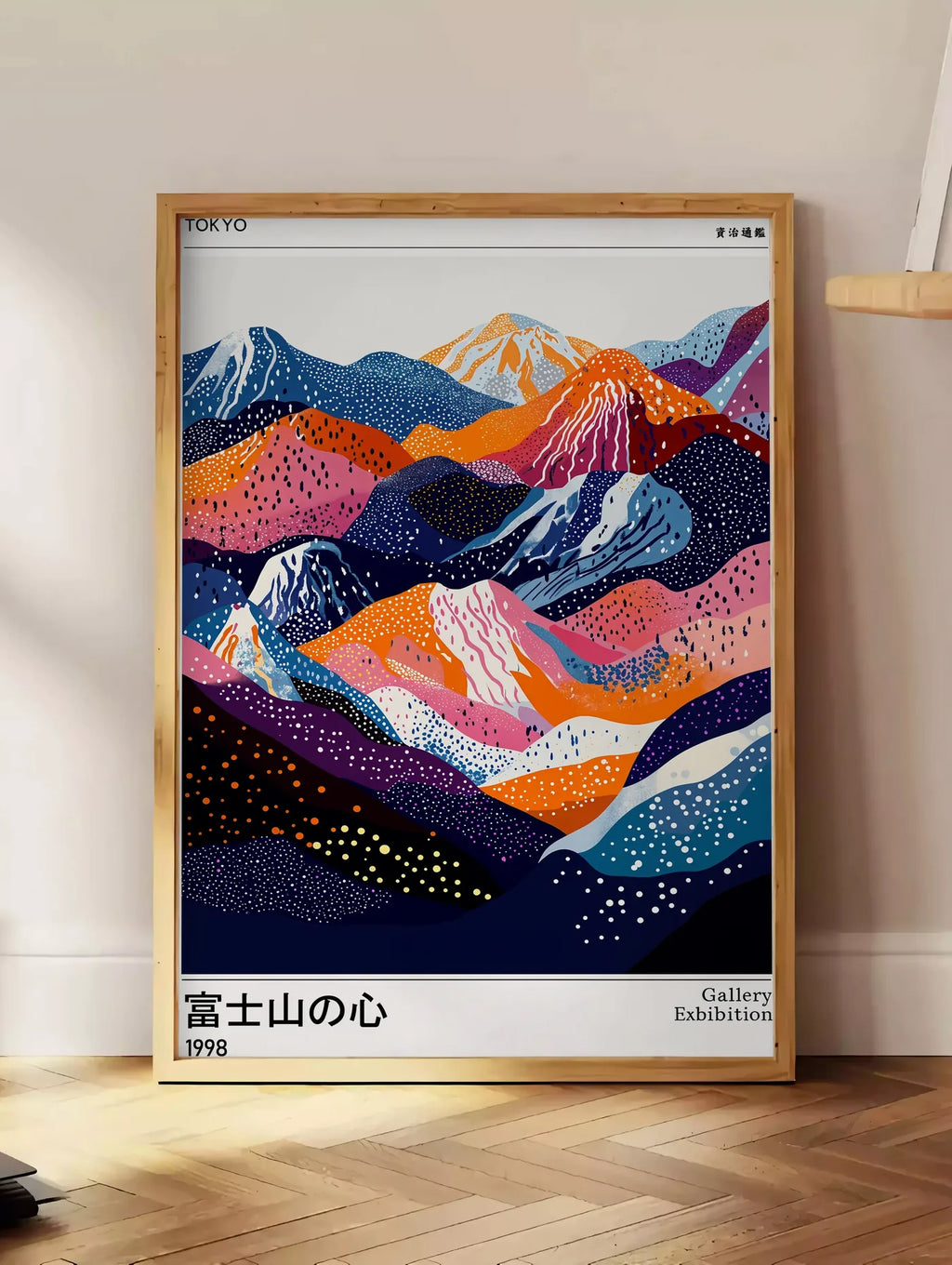 Estampe affiche montagnes du Fuji de Kusama art japonais, posee au sol dans un coin salon, sur un parquet a chevrons, pres d'une table d'appoint en chene chargee de livres