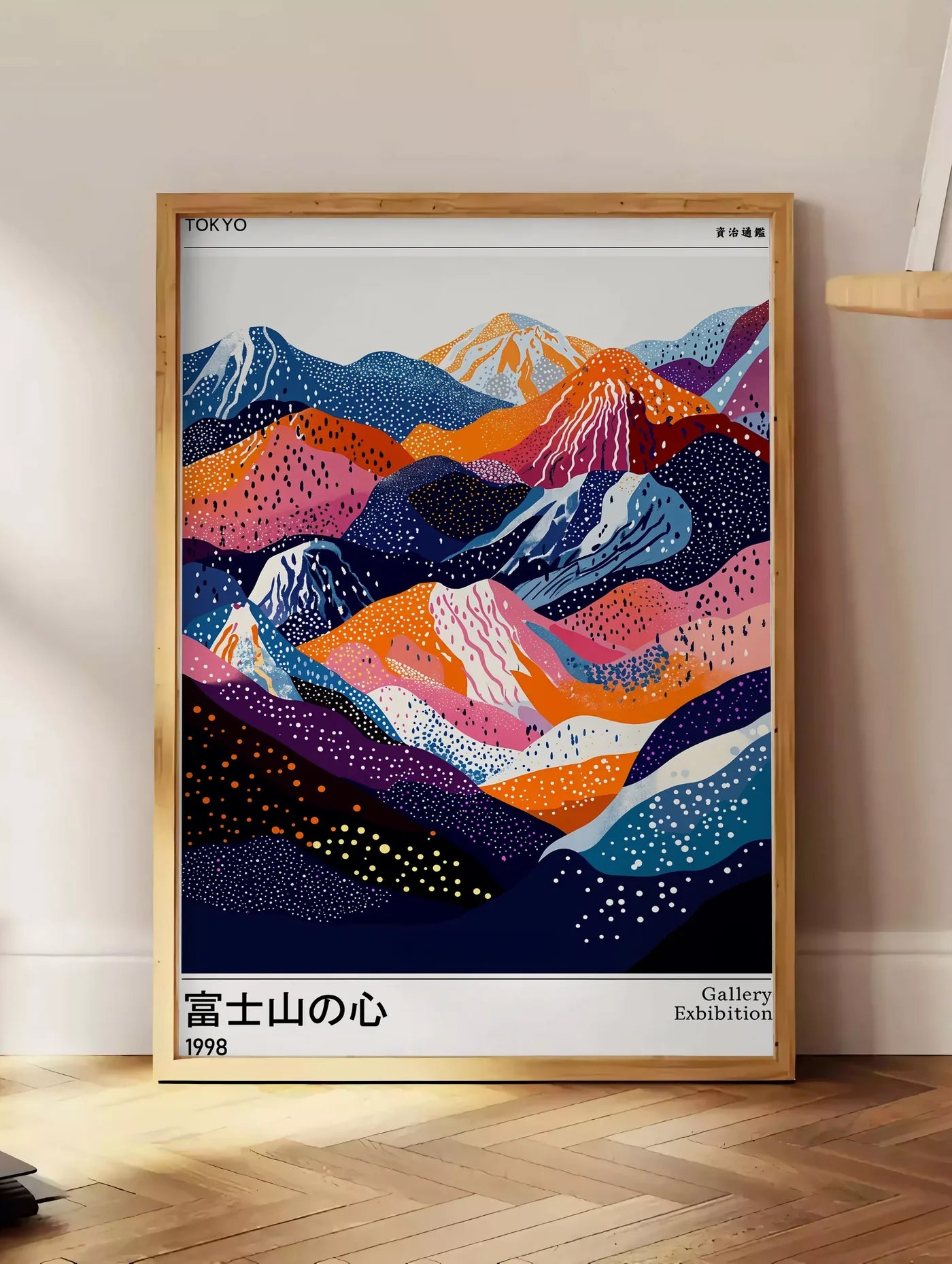 Estampe affiche montagnes du Fuji de Kusama art japonais, posee au sol dans un coin salon, sur un parquet a chevrons, pres d'une table d'appoint en chene chargee de livres