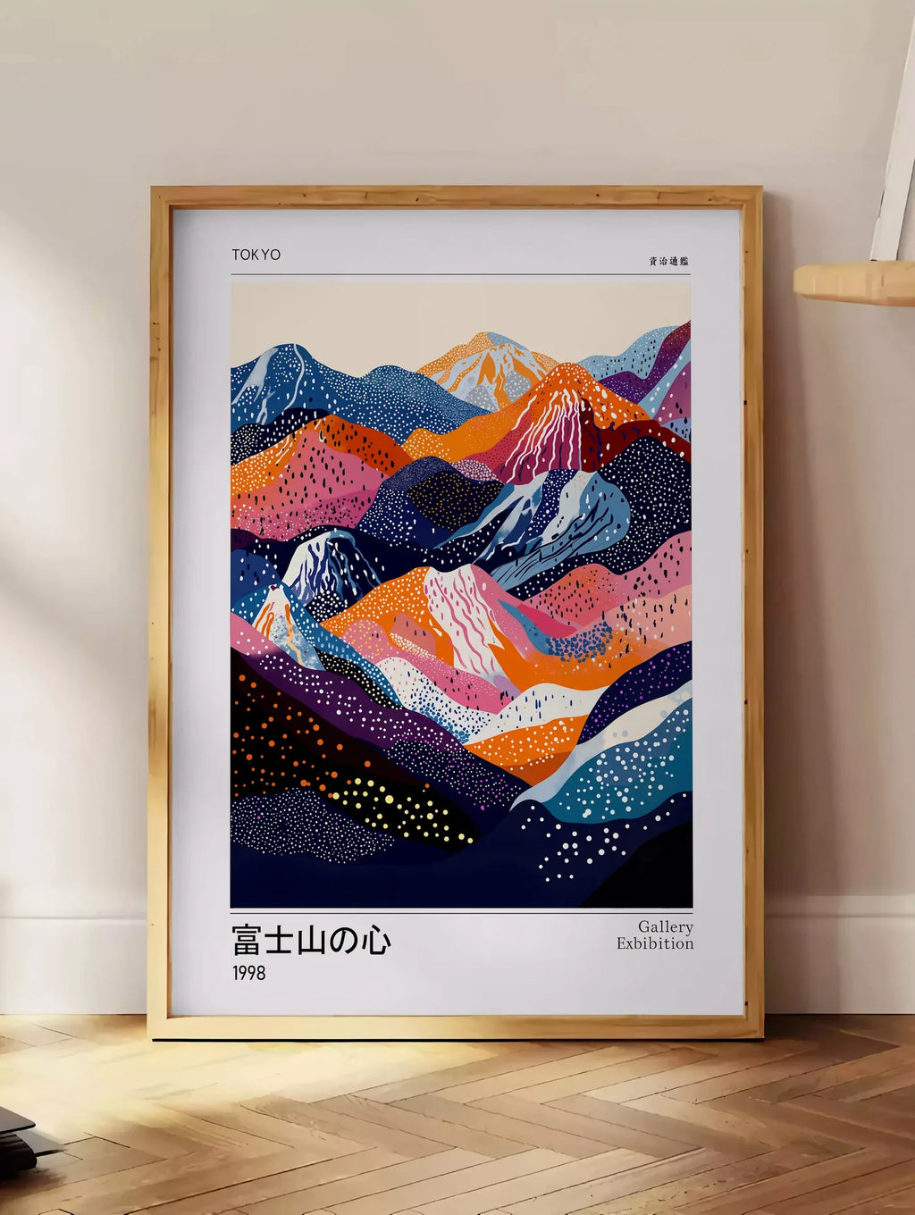 Estampe affiche montagnes a pois de Kusama art japonais, posee au sol dans un coin salon, sur un parquet a chevrons, pres d'une table d'appoint en chene chargee de livres