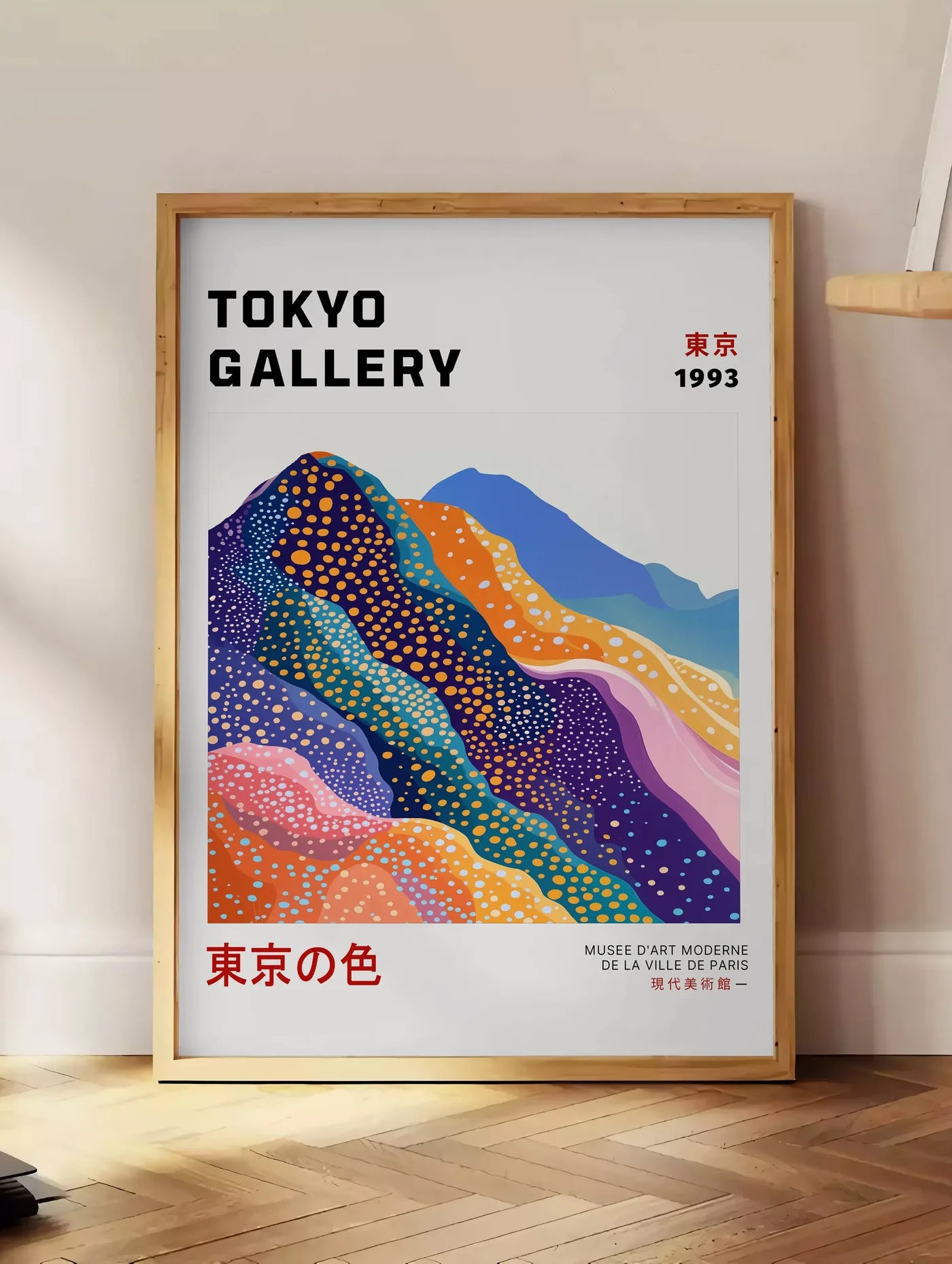 Estampe affiche montagnes Fuji de Kusama art japonais, posee au sol dans un coin salon, sur un parquet a chevrons, pres d'une table d'appoint en chene chargee de livres