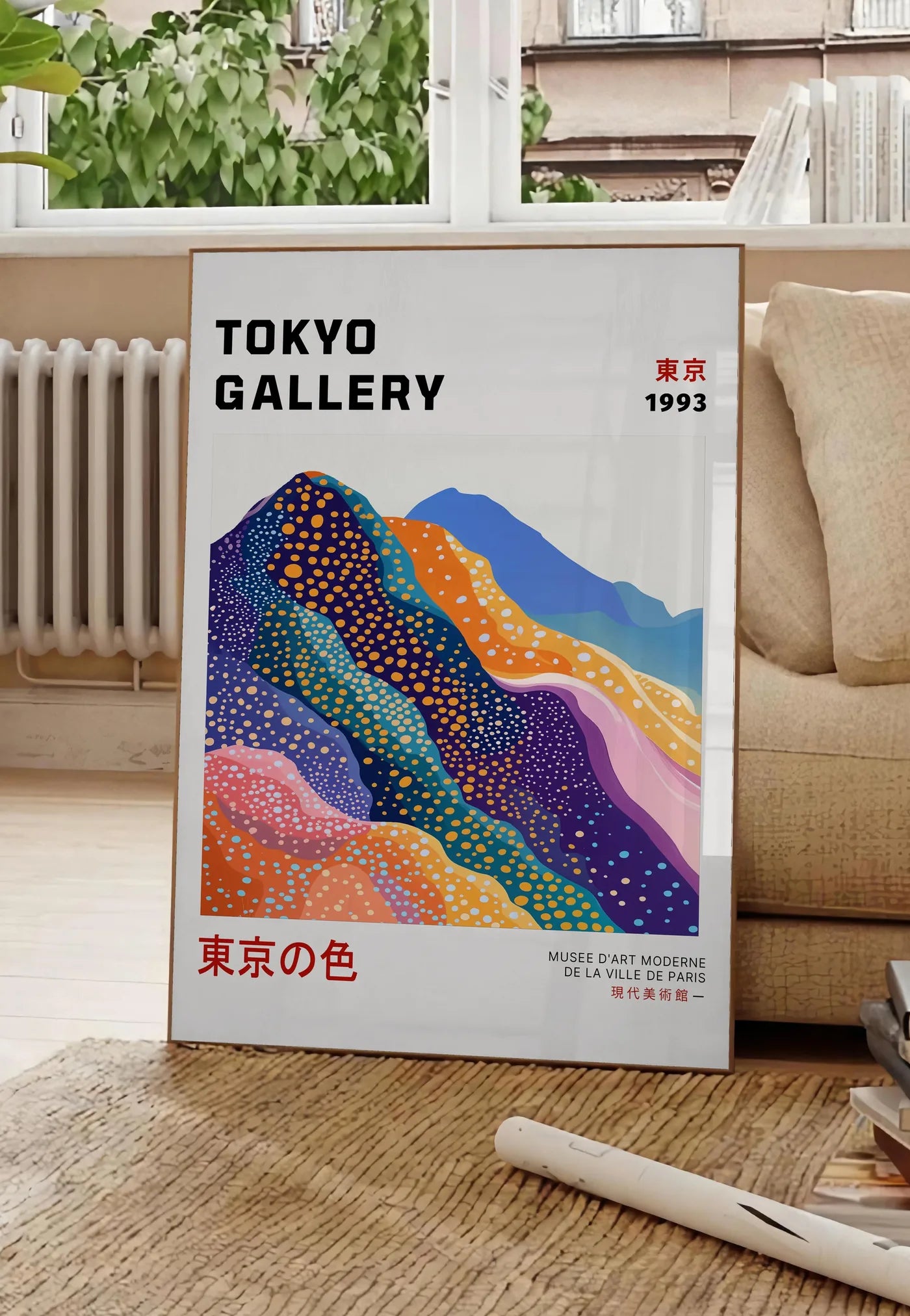 Poster affiche montagnes Fuji de Kusama art japonais, posee au sol dans un salon parisien, devant une grande fenetre donnant sur un immeuble haussmannien, entre un ficus et un canape creme