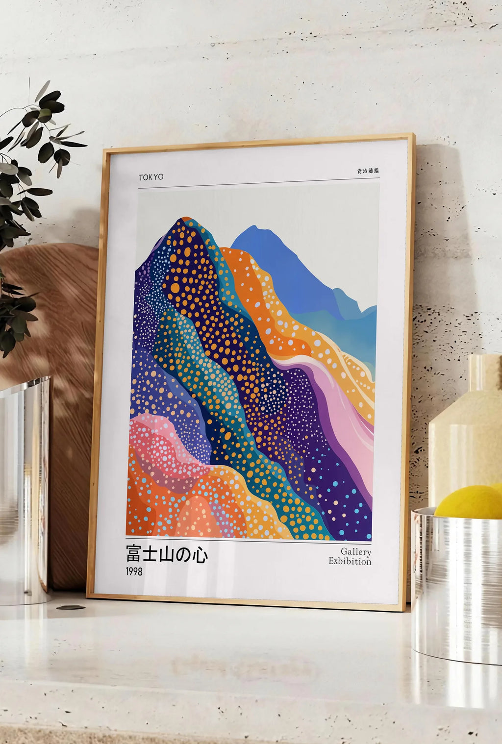Affiche affiche montagnes Fuji de Kusama art japonais, posee sur un plan de travail de cuisine en pierre claire, entre une branche d'eucalyptus en vase et un bocal de citrons