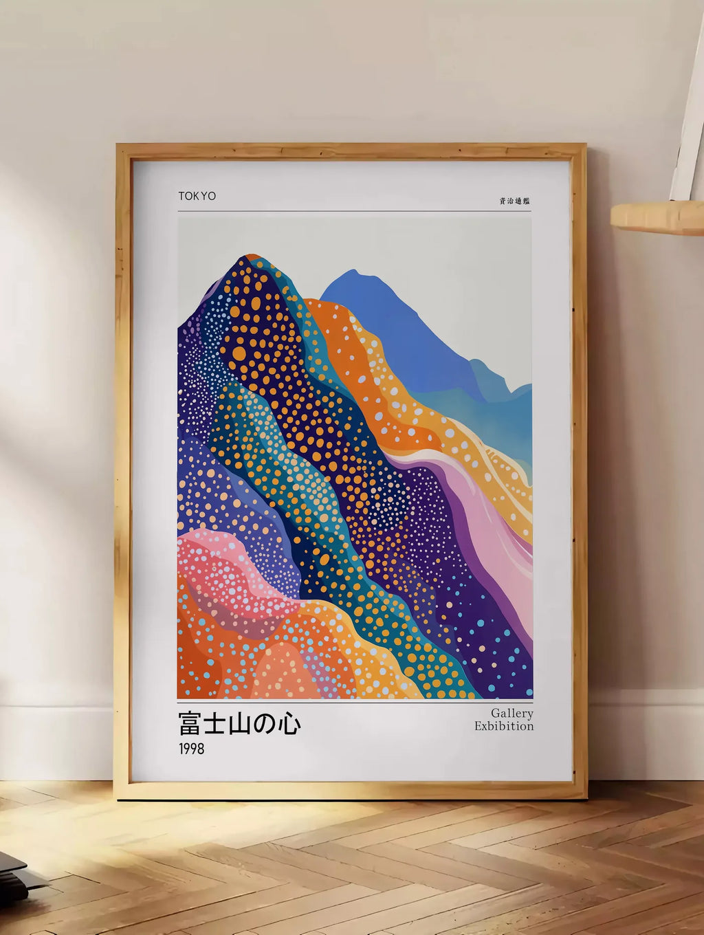 Estampe affiche montagnes Fuji de Kusama art japonais, posee au sol dans un coin salon, sur un parquet a chevrons, pres d'une table d'appoint en chene chargee de livres
