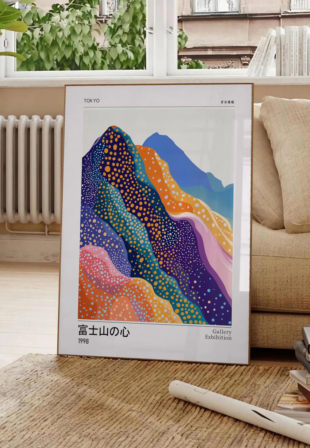 Poster affiche montagnes Fuji de Kusama art japonais, posee au sol dans un salon parisien, devant une grande fenetre donnant sur un immeuble haussmannien, entre un ficus et un canape creme