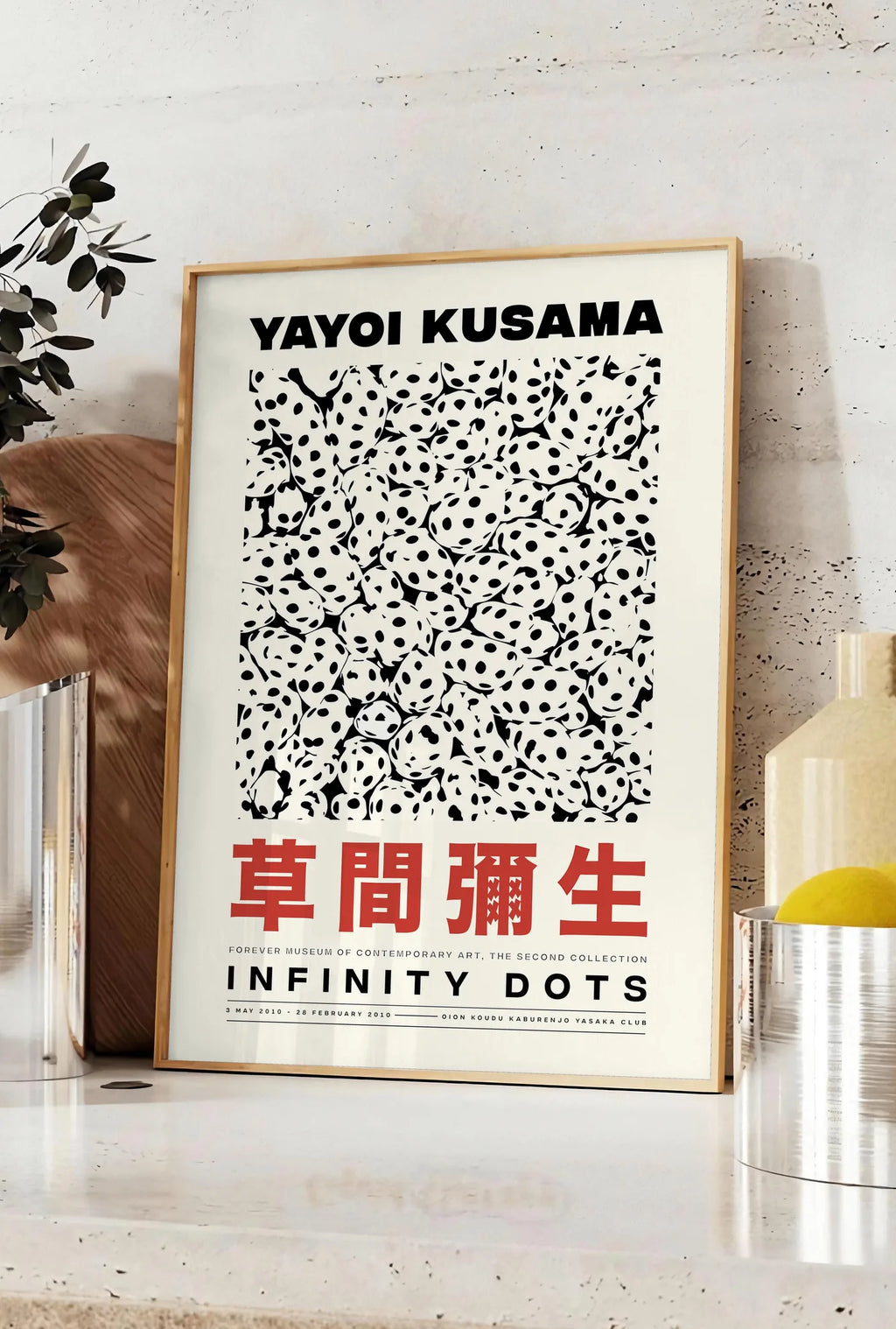 Affiche affiche pois noir et blanc de Kusama art japonais, posee sur un plan de travail de cuisine en pierre claire, entre une branche d'eucalyptus en vase et un bocal de citrons