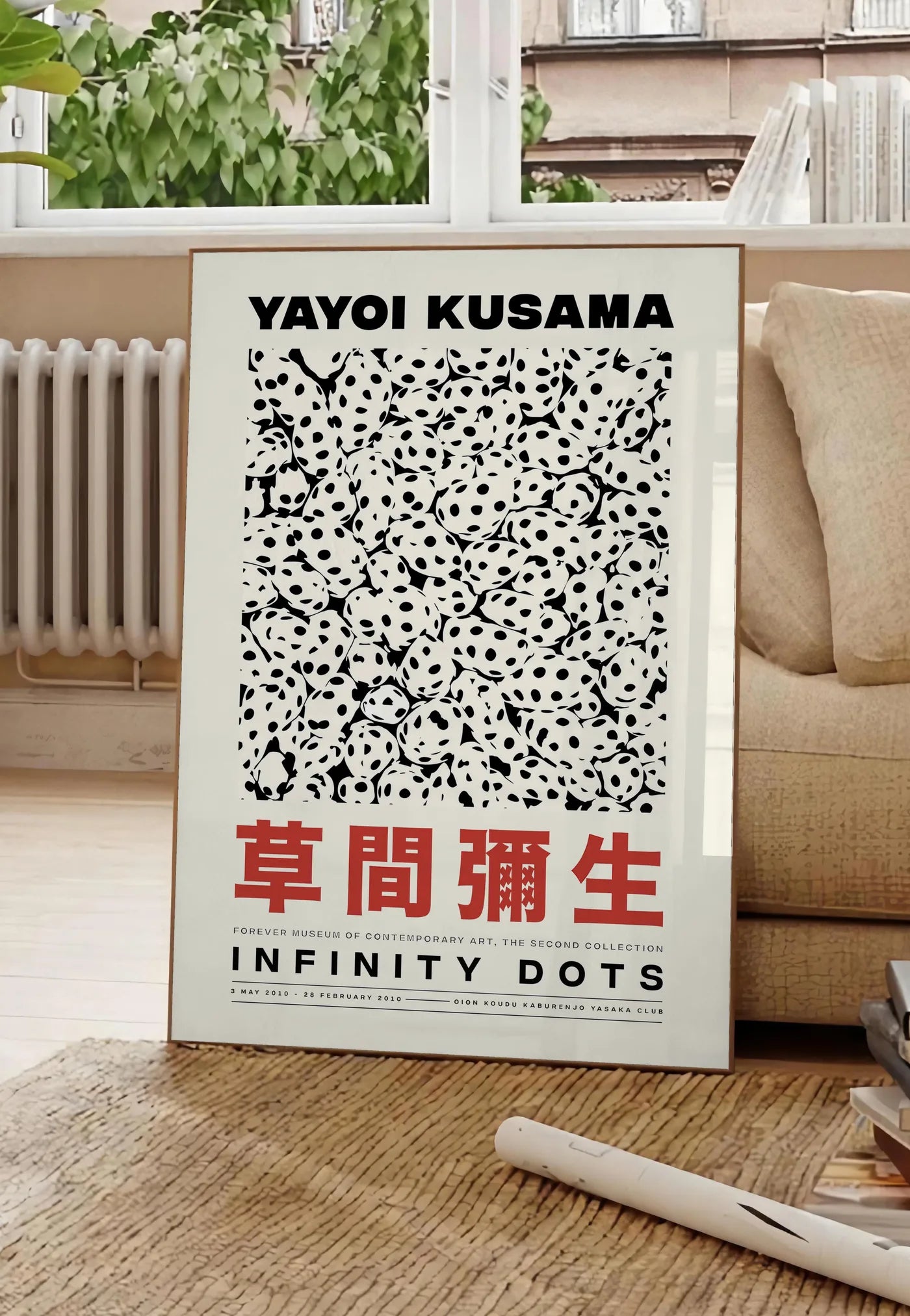 Poster affiche pois noir et blanc de Kusama art japonais, posee au sol dans un salon parisien, devant une grande fenetre donnant sur un immeuble haussmannien, entre un ficus et un canape creme