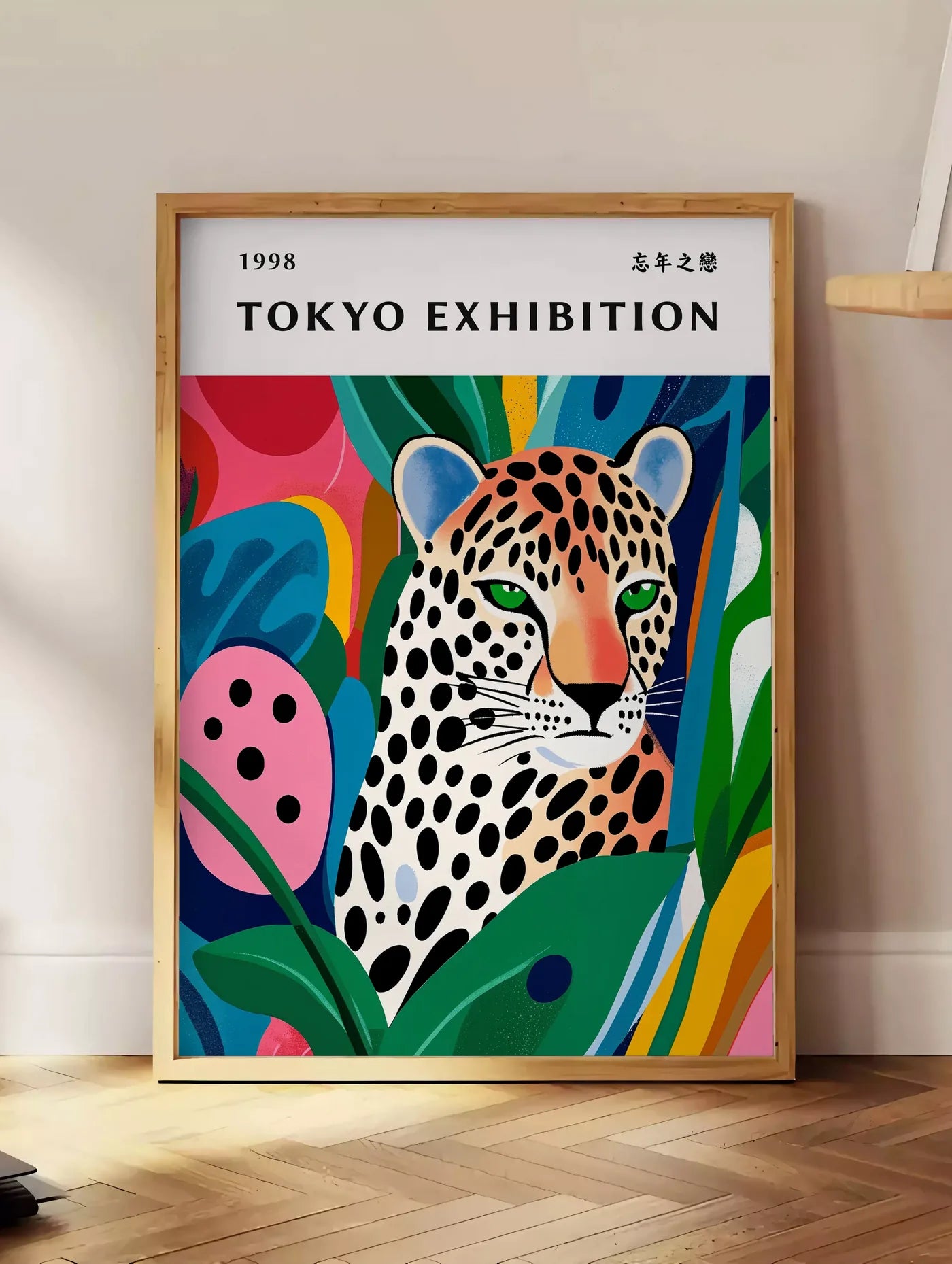 Estampe affiche leopard tachete de Kusama art japonais, posee au sol dans un coin salon, sur un parquet a chevrons, pres d'une table d'appoint en chene chargee de livres