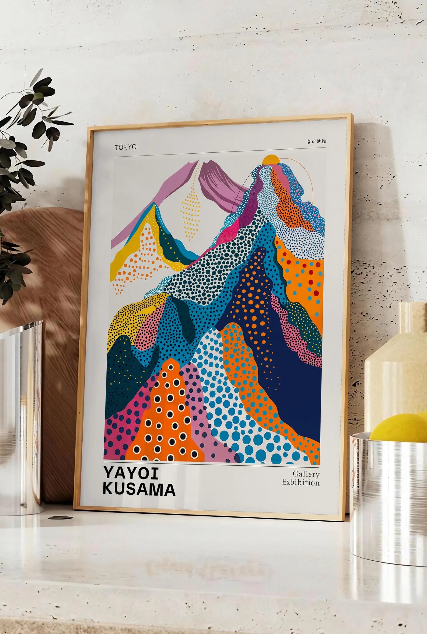 Affiche affiche montagnes multicolores de Kusama art japonais, posee sur un plan de travail de cuisine en pierre claire, entre une branche d'eucalyptus en vase et un bocal de citrons
