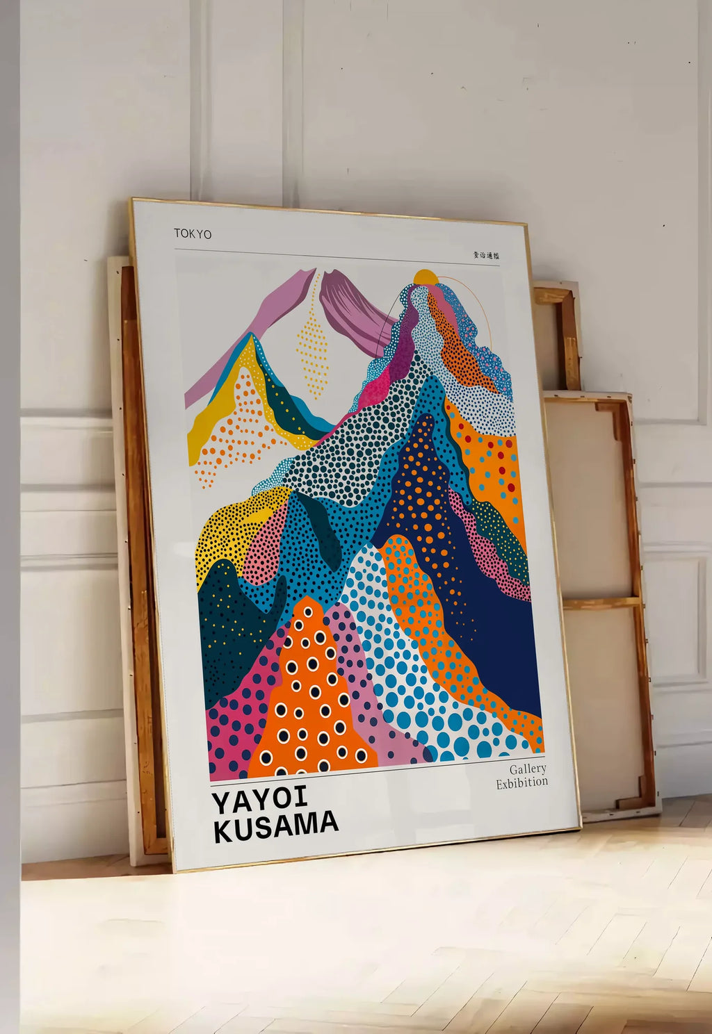 Tirage encadrable affiche montagnes multicolores de Kusama art japonais, posee au sol dans une entree lumineuse, contre un mur a panneaux blancs, a cote de chassis en bois empiles
