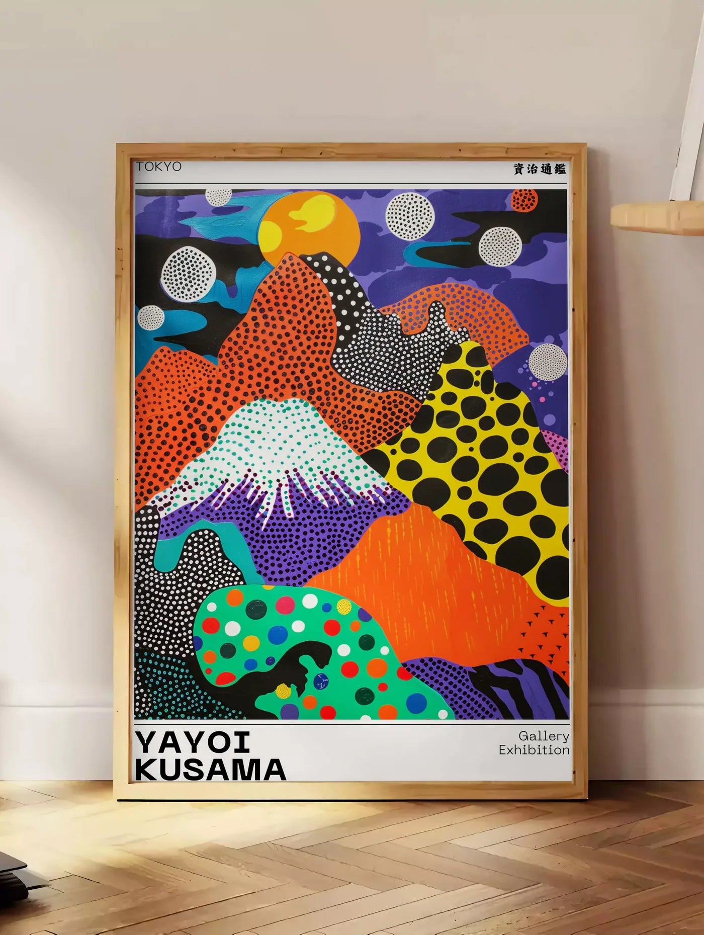 Estampe affiche paysage a pois de Kusama art japonais, posee au sol dans un coin salon, sur un parquet a chevrons, pres d'une table d'appoint en chene chargee de livres