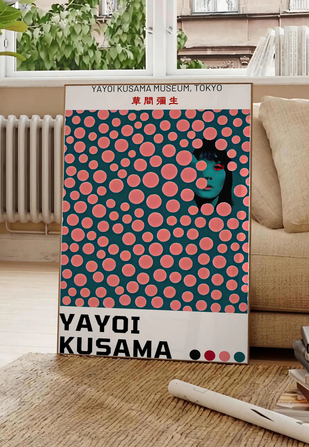 Poster affiche pois corail de Kusama art japonais, posee au sol dans un salon parisien, devant une grande fenetre donnant sur un immeuble haussmannien, entre un ficus et un canape creme