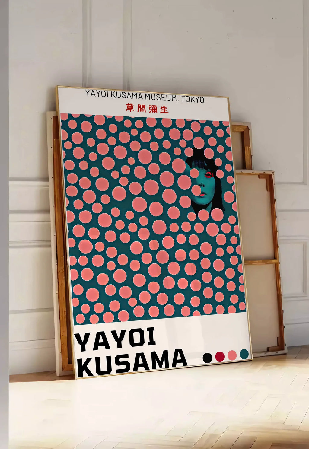 Tirage encadrable affiche pois corail de Kusama art japonais, posee au sol dans une entree lumineuse, contre un mur a panneaux blancs, a cote de chassis en bois empiles