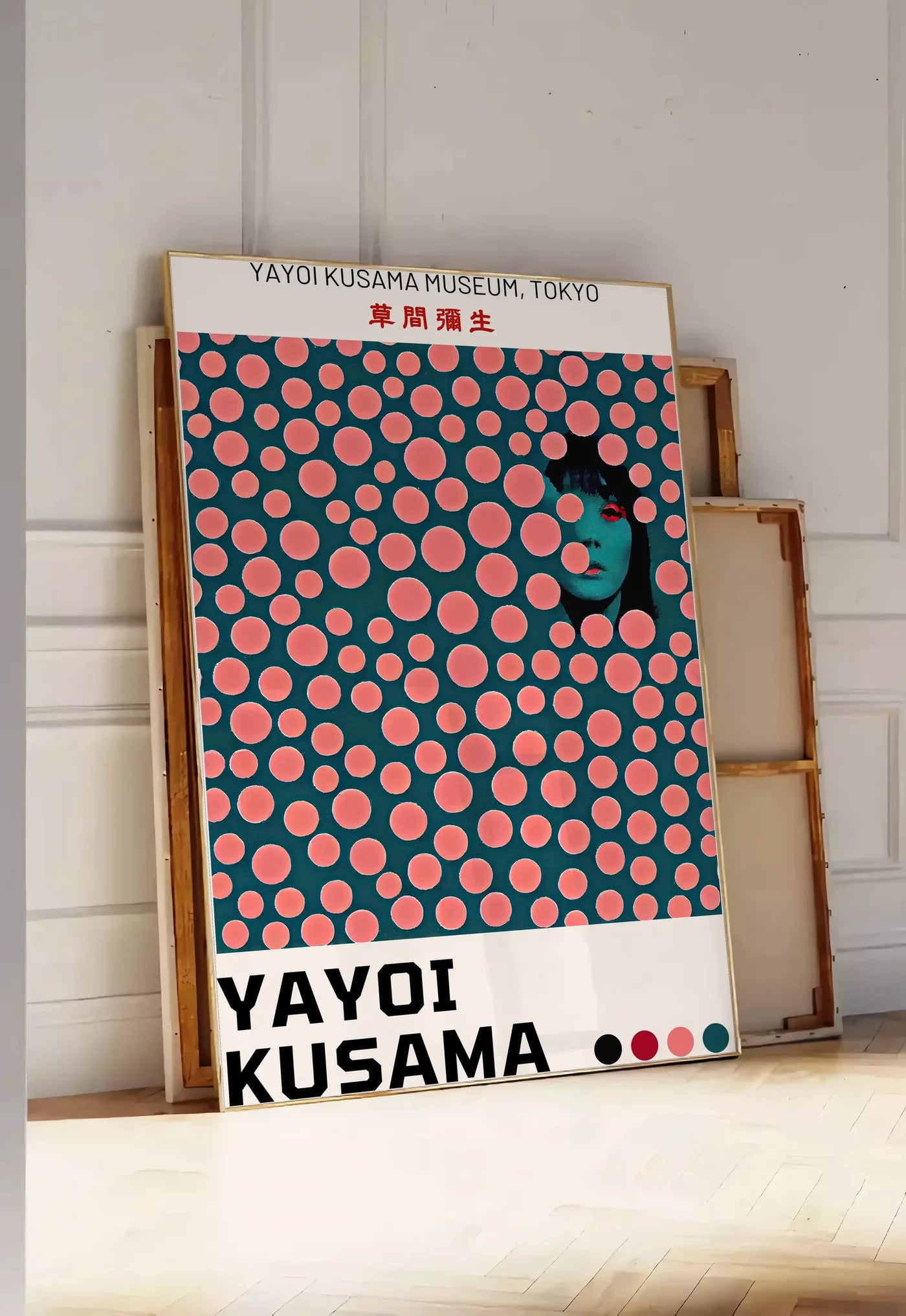 Tirage encadrable affiche pois corail de Kusama art japonais, posee au sol dans une entree lumineuse, contre un mur a panneaux blancs, a cote de chassis en bois empiles