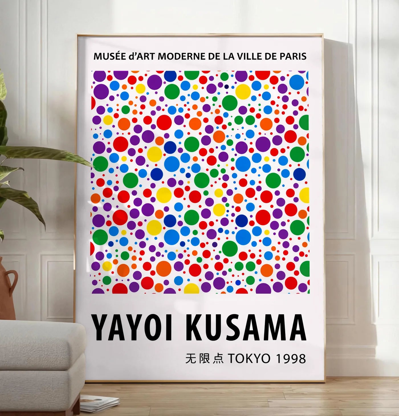 Reproduction affiche pois multicolores de Kusama art japonais, posee au sol dans un salon minimaliste clair, a cote d'un canape beige et d'une plante verte, sur un parquet clair