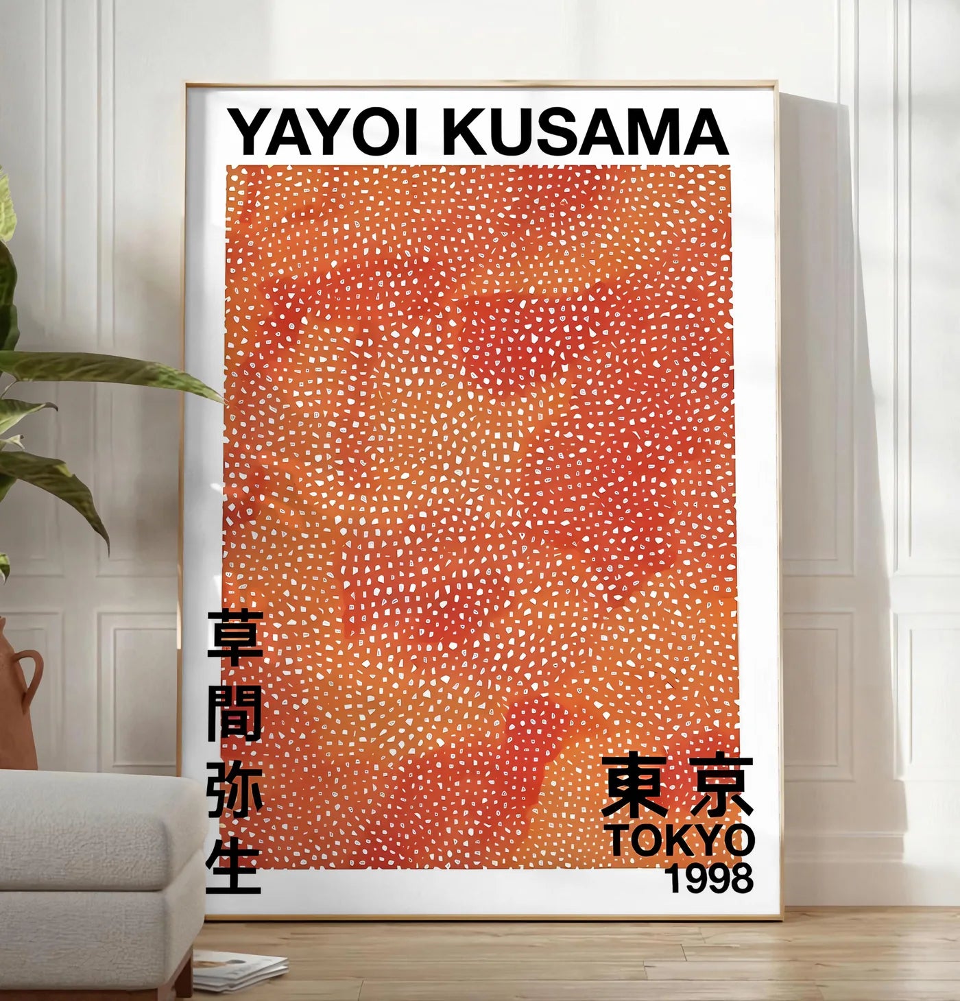 Reproduction affiche pois orange de Kusama art japonais, posee au sol dans un salon minimaliste clair, a cote d'un canape beige et d'une plante verte, sur un parquet clair
