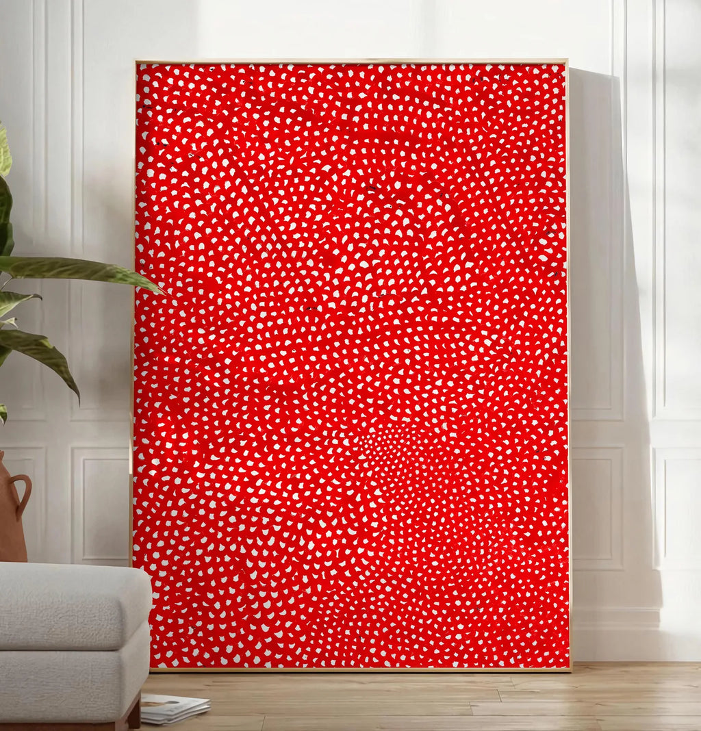 Reproduction affiche pois rouge et blanc de Kusama art japonais, posee au sol dans un salon minimaliste clair, a cote d'un canape beige et d'une plante verte, sur un parquet clair