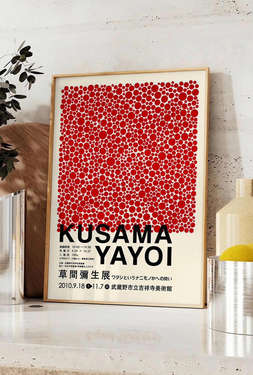 Affiche affiche pois rouges de Kusama art japonais, posee sur un plan de travail de cuisine en pierre claire, entre une branche d'eucalyptus en vase et un bocal de citrons