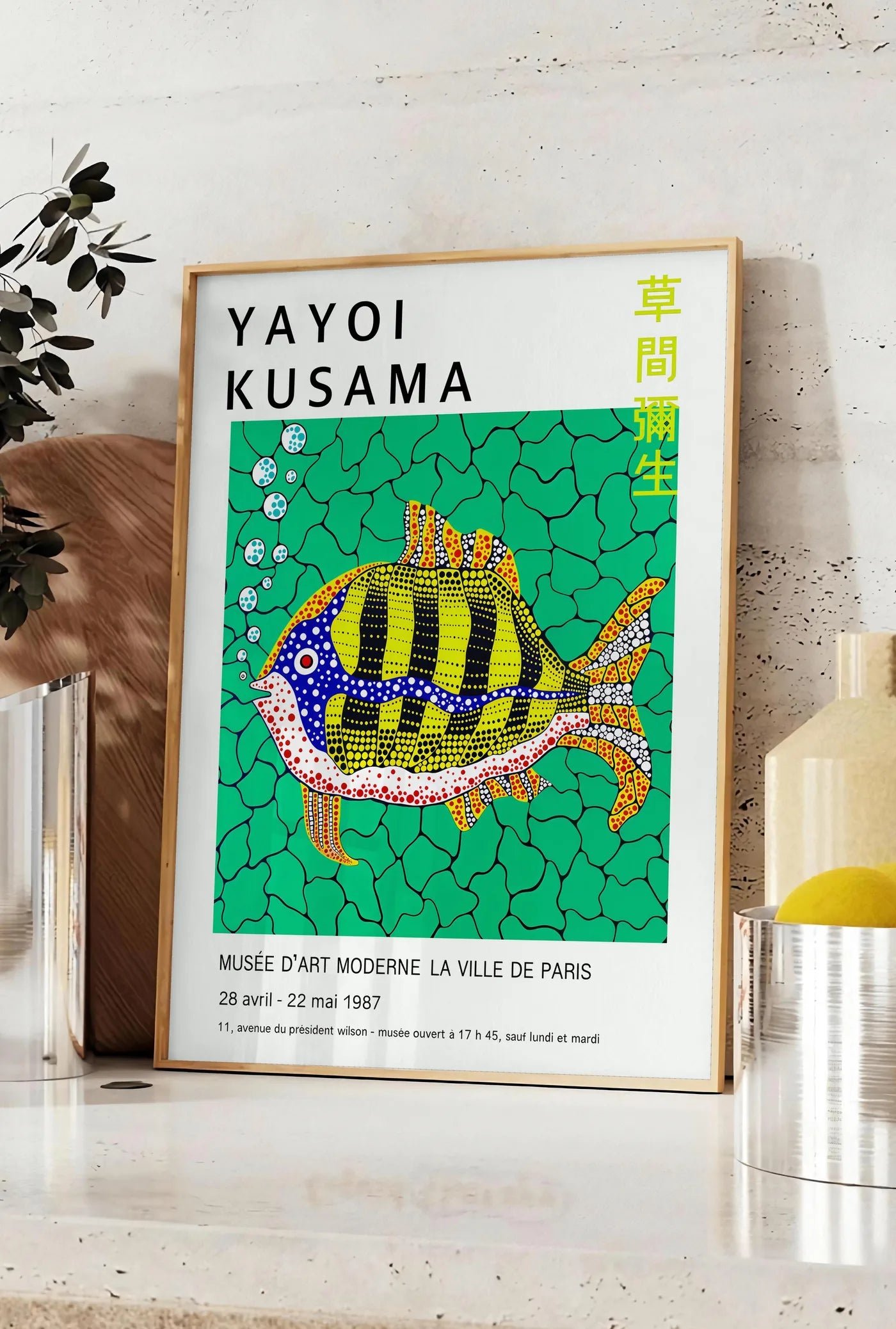 Affiche affiche poisson a pois de Kusama art japonais, posee sur un plan de travail de cuisine en pierre claire, entre une branche d'eucalyptus en vase et un bocal de citrons