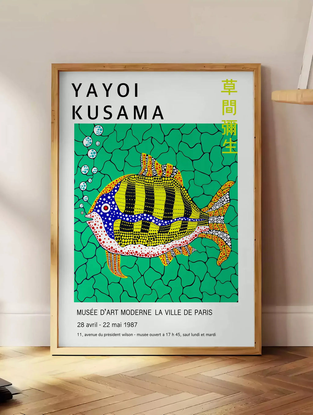 Estampe affiche poisson a pois de Kusama art japonais, posee au sol dans un coin salon, sur un parquet a chevrons, pres d'une table d'appoint en chene chargee de livres