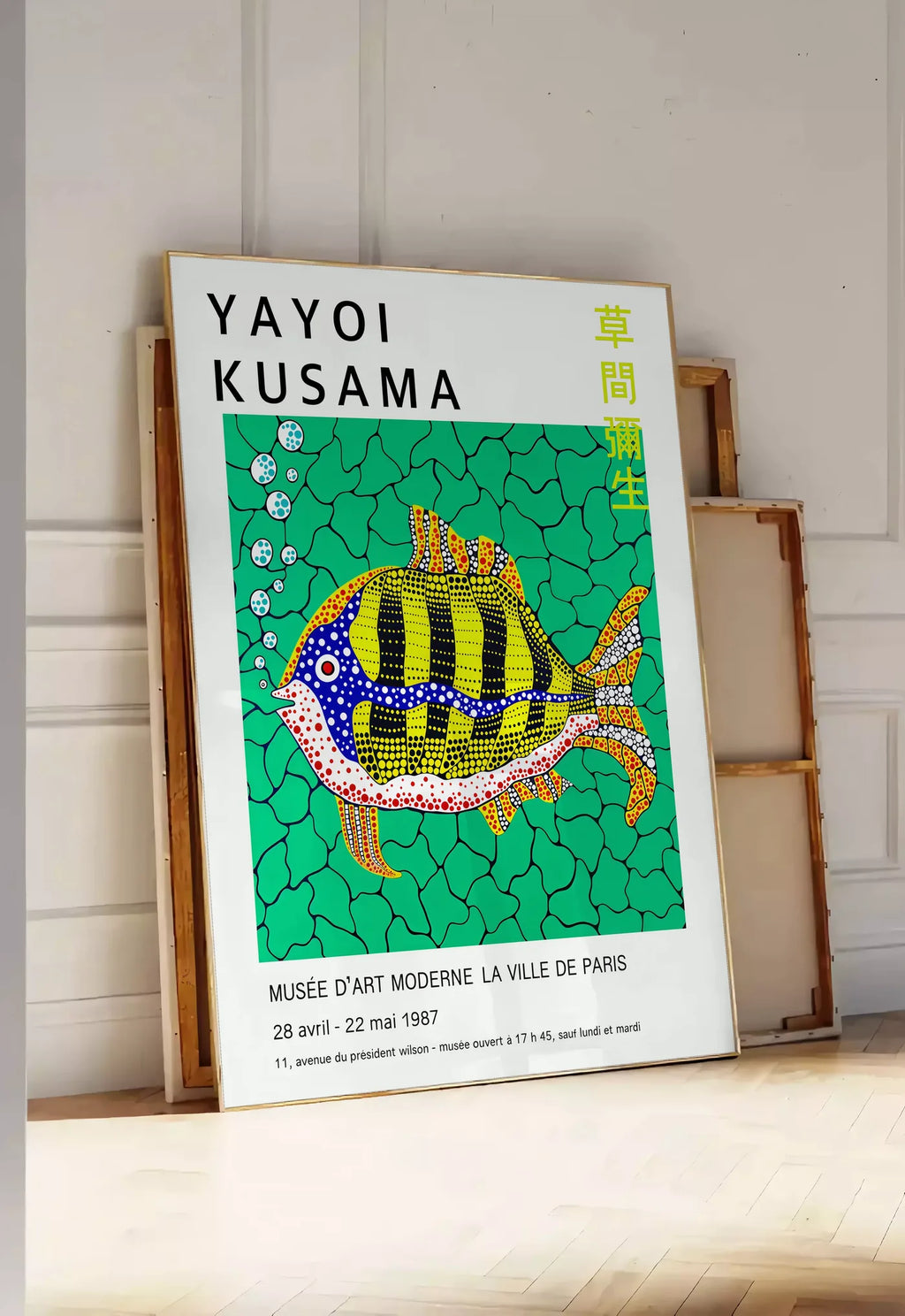 Tirage encadrable affiche poisson a pois de Kusama art japonais, posee au sol dans une entree lumineuse, contre un mur a panneaux blancs, a cote de chassis en bois empiles