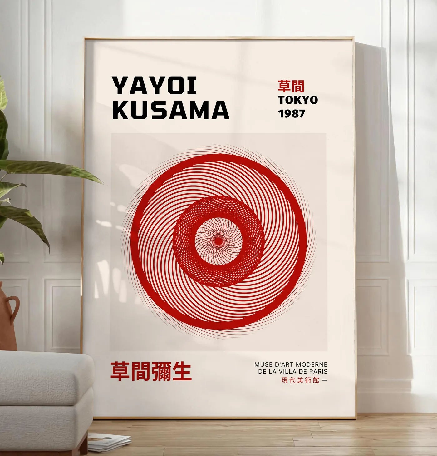 Reproduction affiche spirale rouge de Kusama art japonais, posee au sol dans un salon minimaliste clair, a cote d'un canape beige et d'une plante verte, sur un parquet clair
