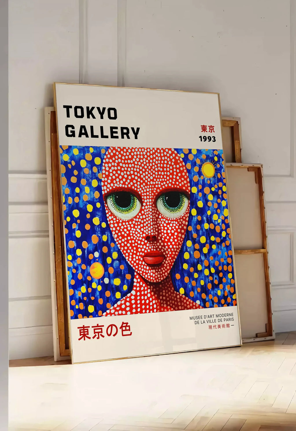 Tirage encadrable affiche visage de femme a pois de Kusama art japonais, posee au sol dans une entree lumineuse, contre un mur a panneaux blancs, a cote de chassis en bois empiles