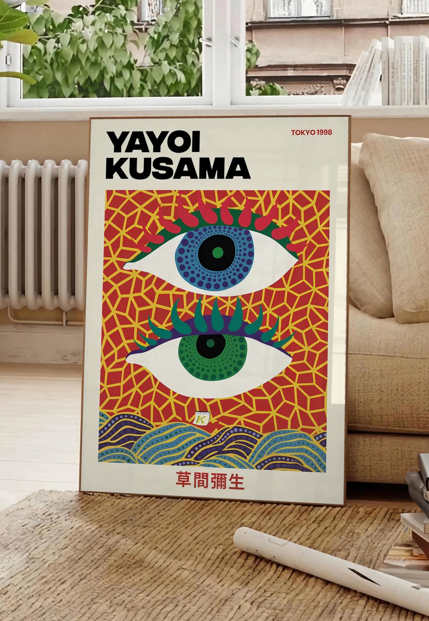 Poster affiche yeux a pois de Kusama art japonais, posee au sol dans un salon parisien, devant une grande fenetre donnant sur un immeuble haussmannien, entre un ficus et un canape creme