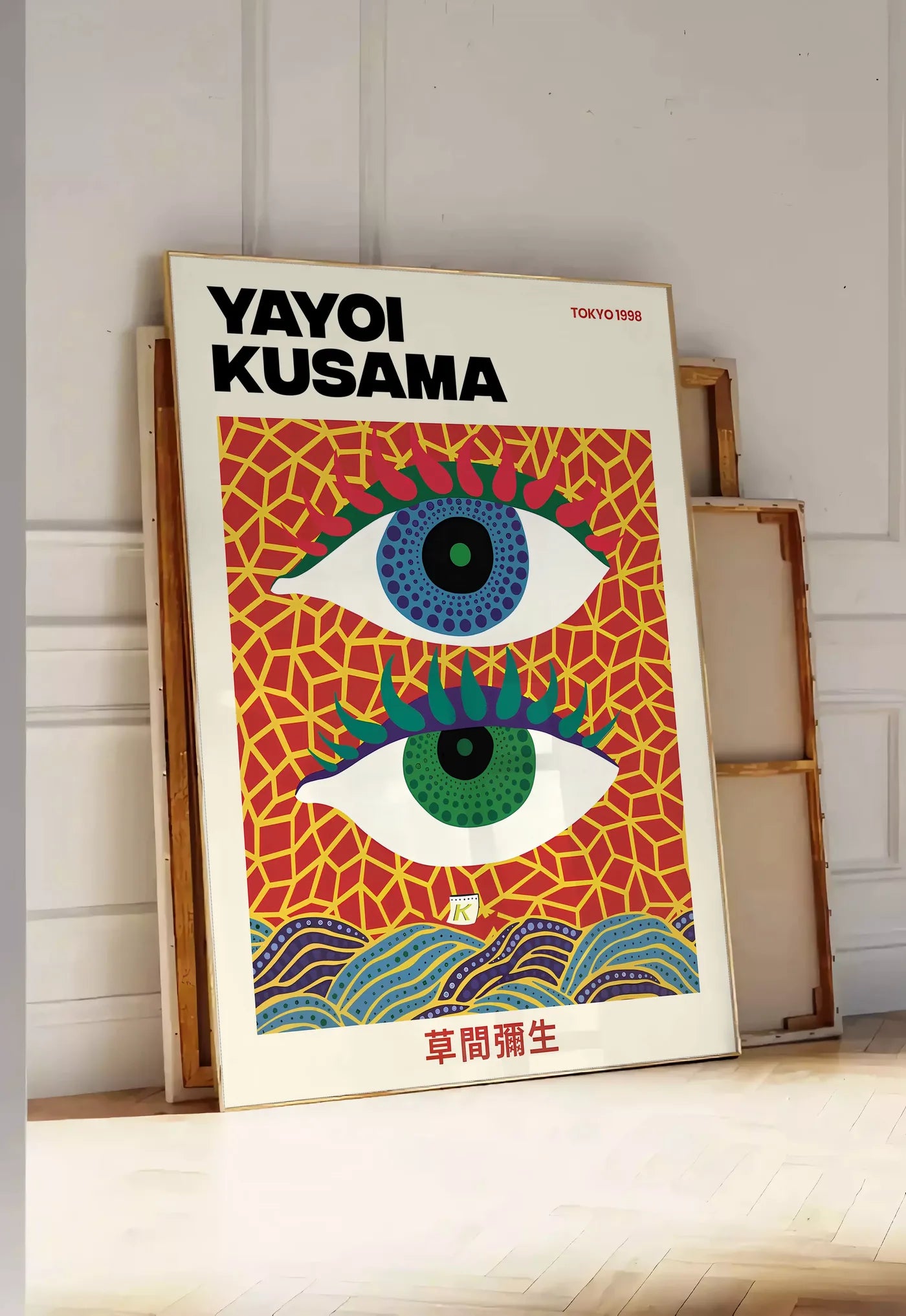 Tirage encadrable affiche yeux a pois de Kusama art japonais, posee au sol dans une entree lumineuse, contre un mur a panneaux blancs, a cote de chassis en bois empiles