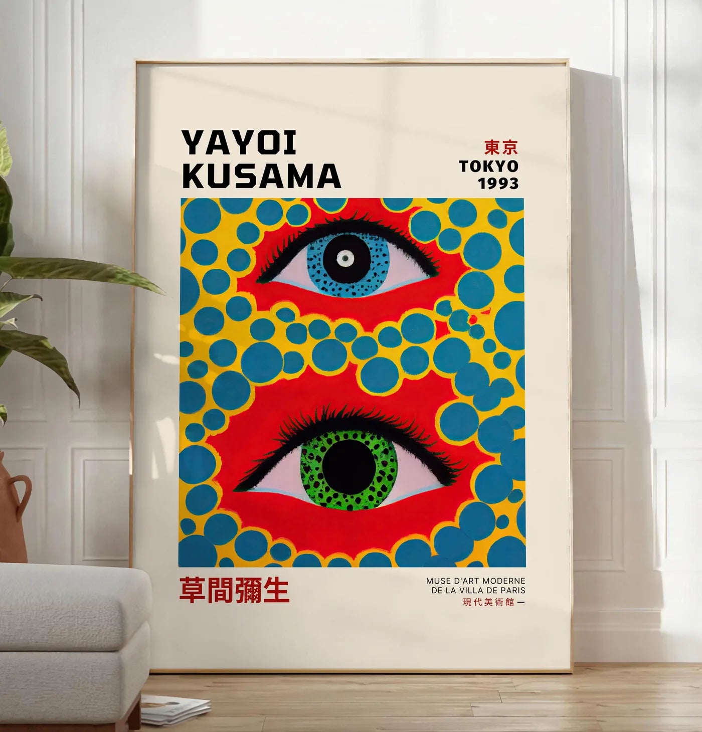 Reproduction affiche yeux a pois jaune de Kusama art japonais, posee au sol dans un salon minimaliste clair, a cote d'un canape beige et d'une plante verte, sur un parquet clair