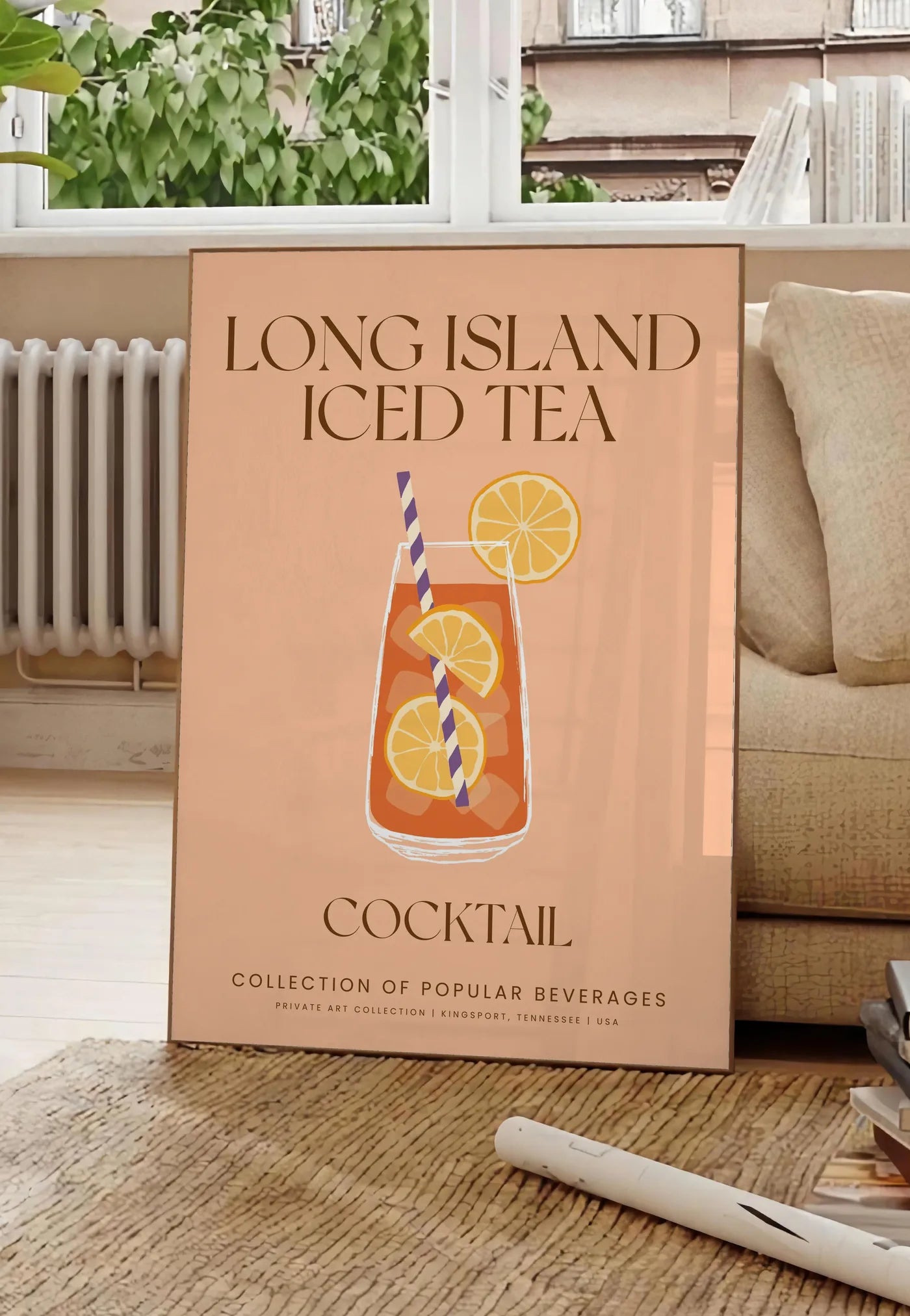 Poster affiche cocktail Long Island Iced Tea, posee au sol dans un salon parisien, devant une grande fenetre donnant sur un immeuble haussmannien, entre un ficus et un canape creme