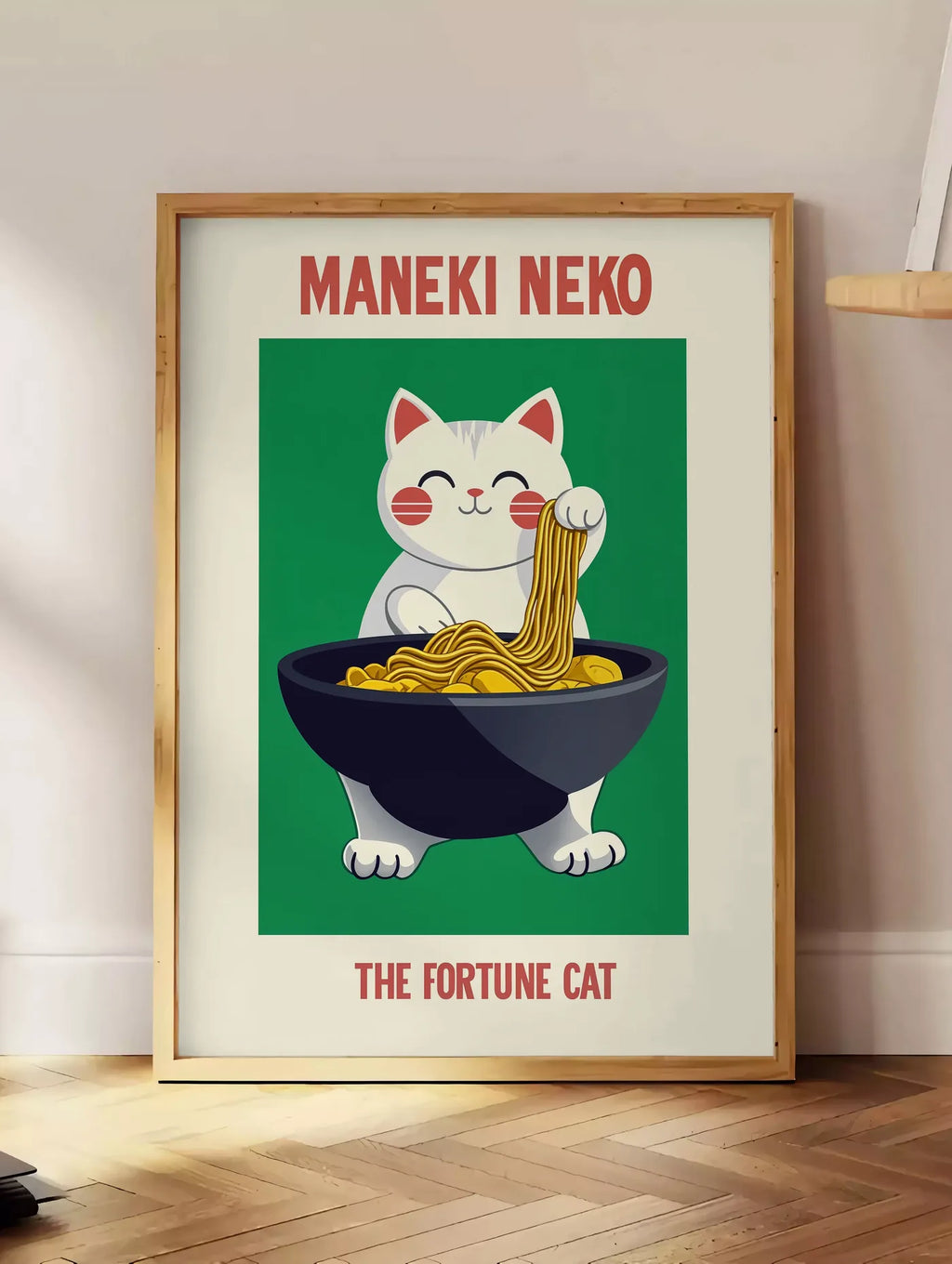 Estampe affiche Maneki Neko chat porte-bonheur tirant un fil de ramen d'un grand bol noir, posee au sol dans un coin salon, sur un parquet a chevrons, pres d'une table d'appoint en chene chargee de livres