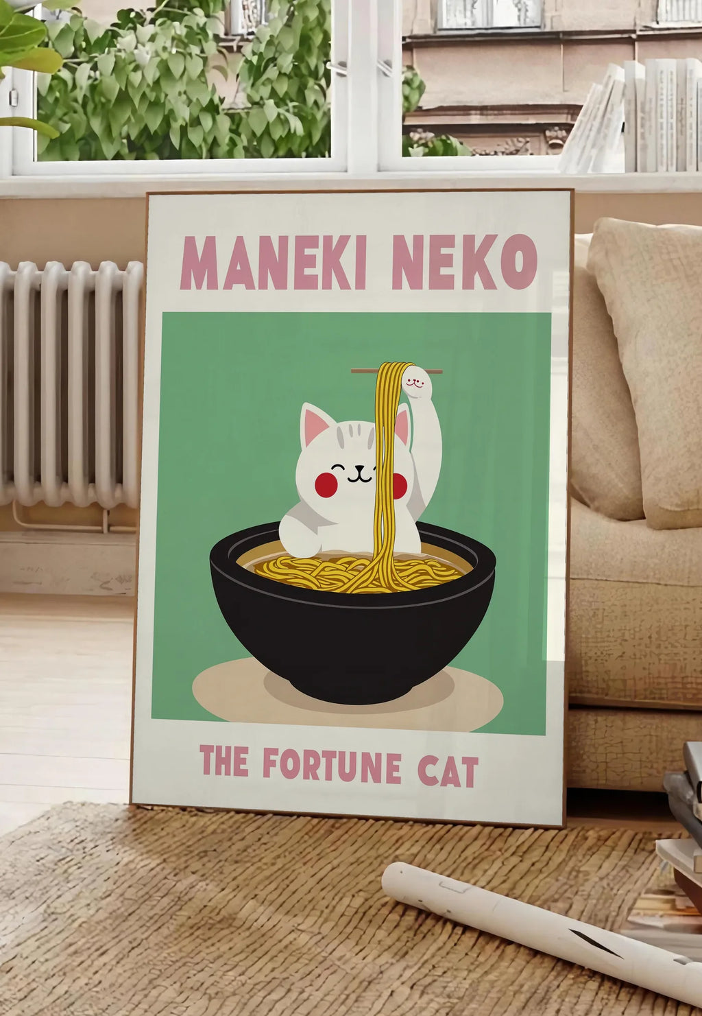 Poster affiche Maneki Neko chat et ramen sur fond vert sauge, posee au sol dans un salon parisien, devant une grande fenetre donnant sur un immeuble haussmannien, entre un ficus et un canape creme